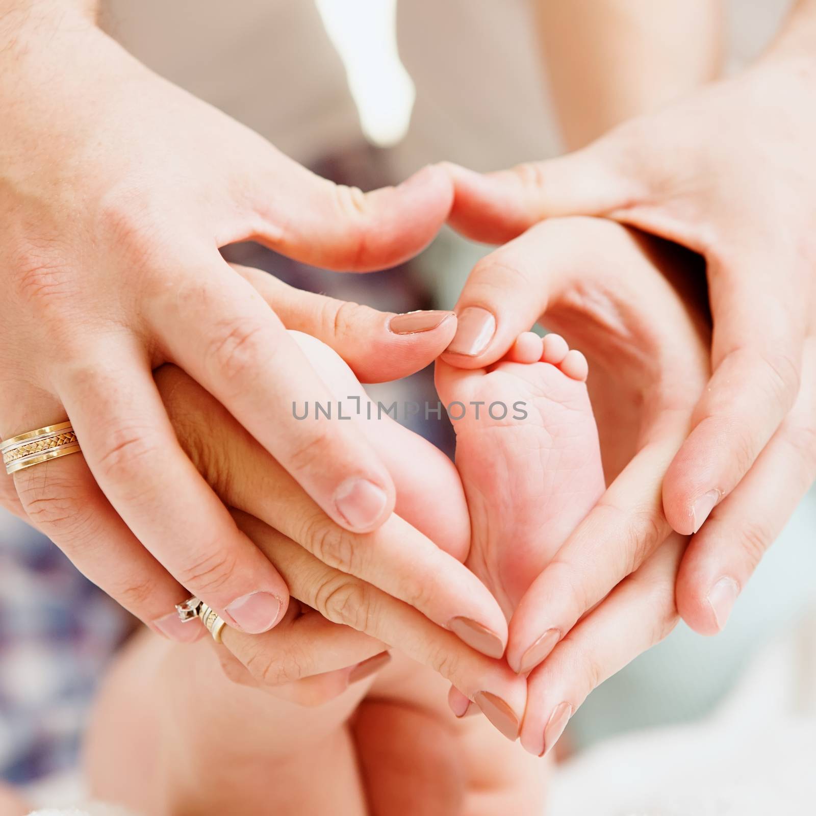 Children&amp;#39;s feet in hands of mother and father. Feet of the tiny Newborn Child  up of hands of a warm form. Parents and Child. Happy Family concept. Beautiful conceptual image of Motherhood