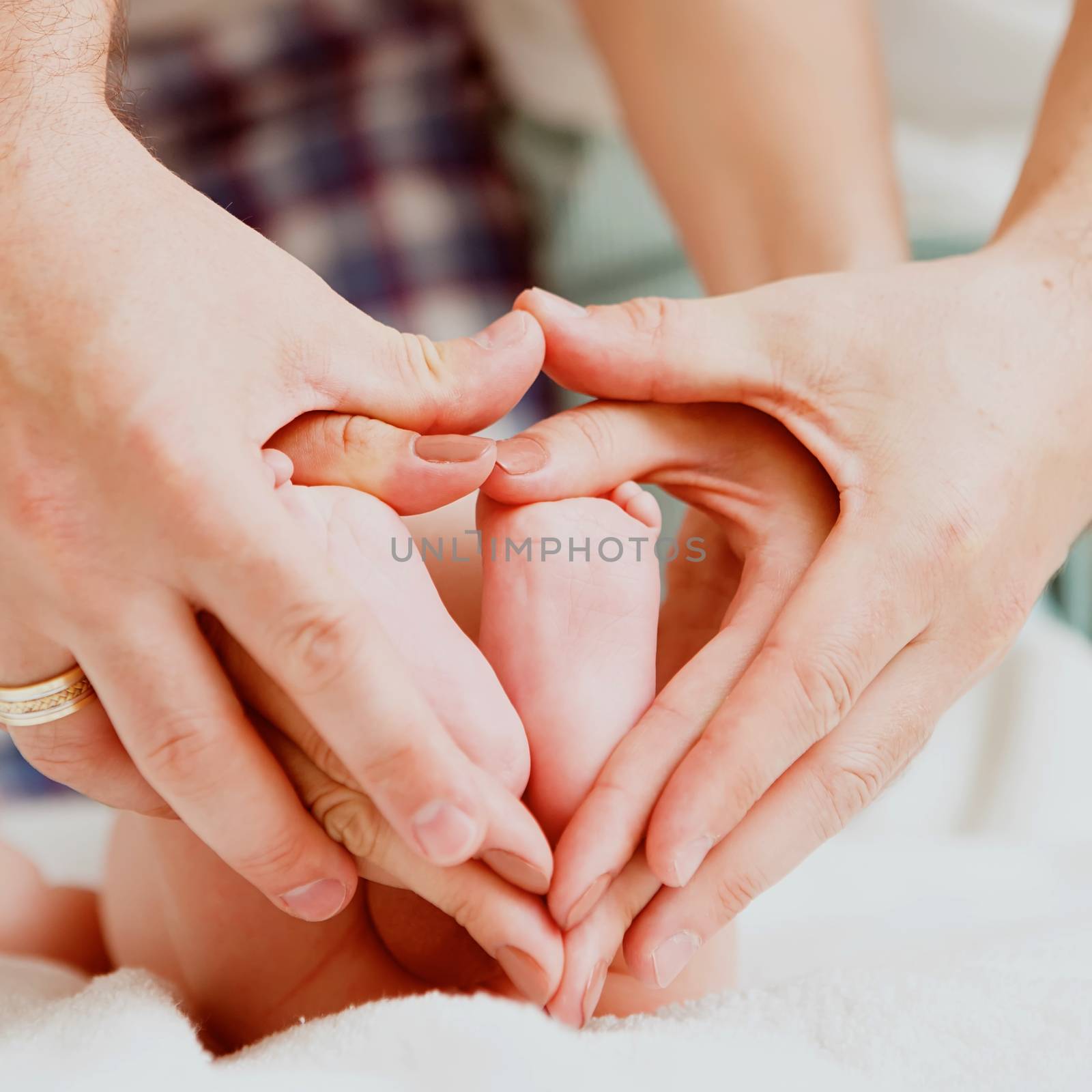 Children&amp;#39;s feet in hands of mother and father. Feet of the tiny Newborn Child  up of hands of a warm form. Parents and Child. Happy Family concept. Beautiful conceptual image of Motherhood