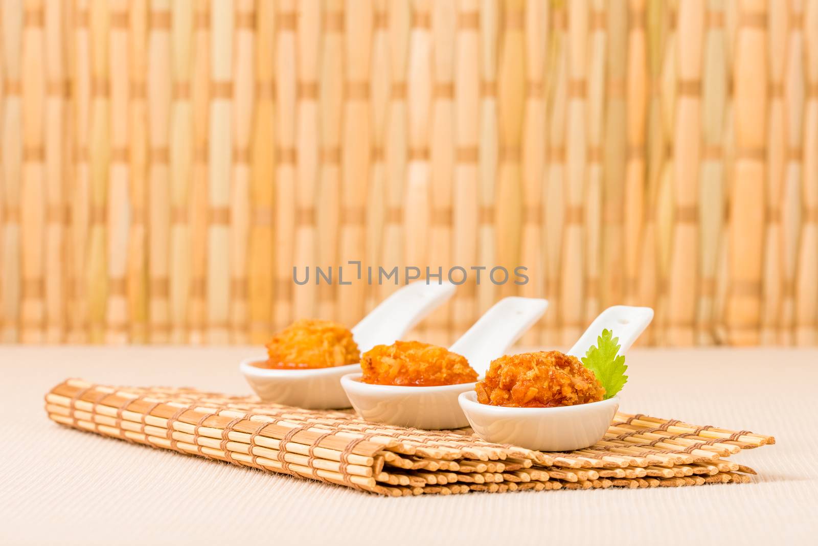 Coconut crusted chicken with dipping sauce with a background of bamboo.