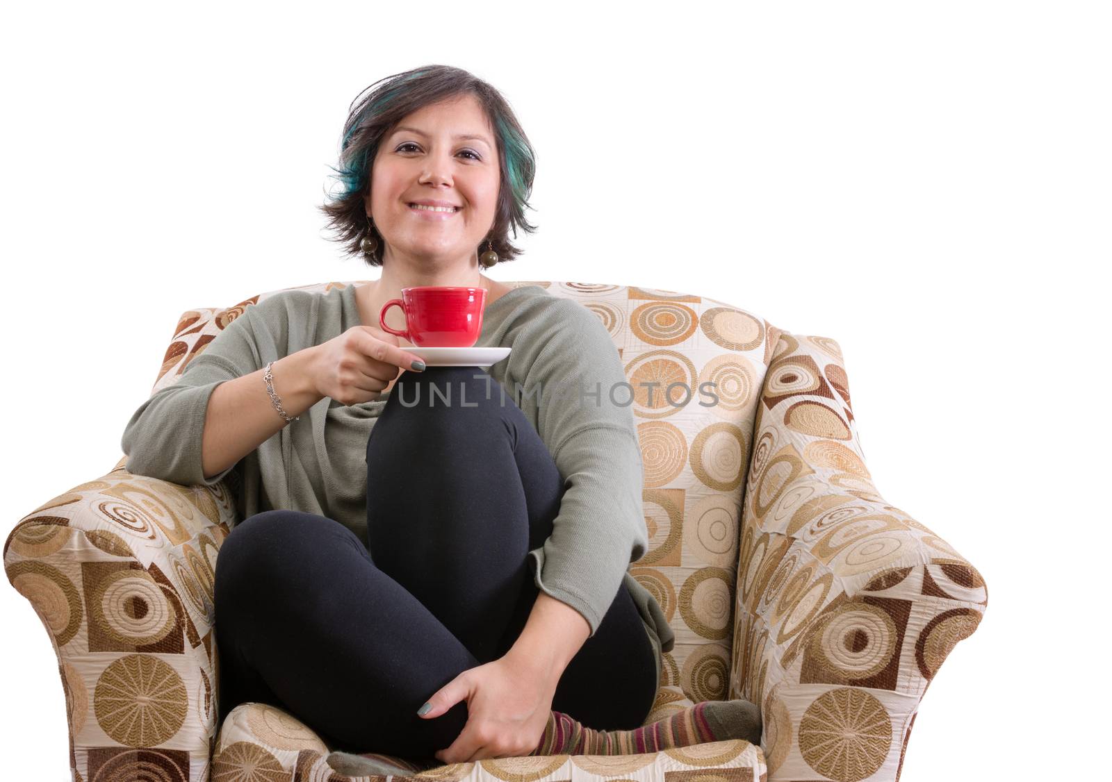 Single adult woman with smile sitting with red mug and crossed legs in sofa chair over white background
