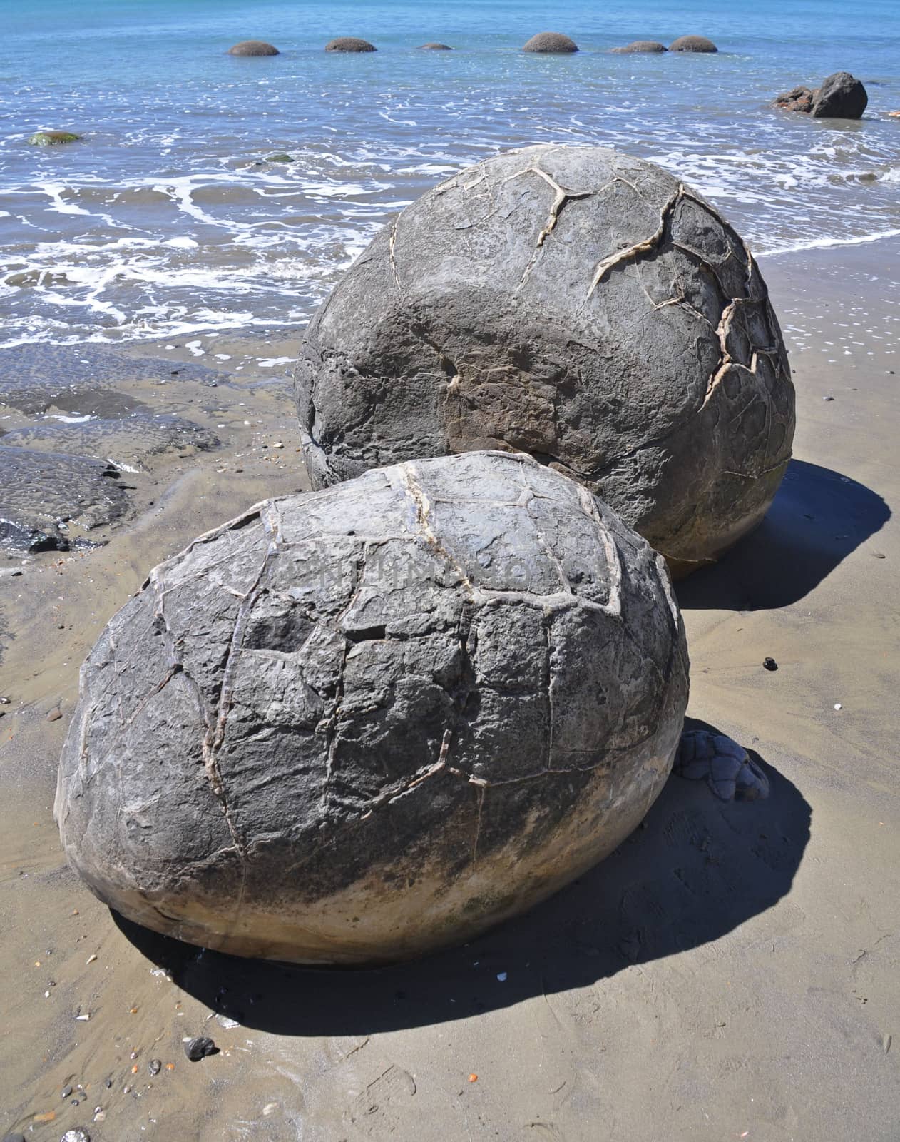 Moeraki Boulders are perfectly spherical rocks on the beach at Moeraki, north of Dunedin, near Oamaru. Up to 13 feet round Maori believe they were food baskets on the original Maori canoe