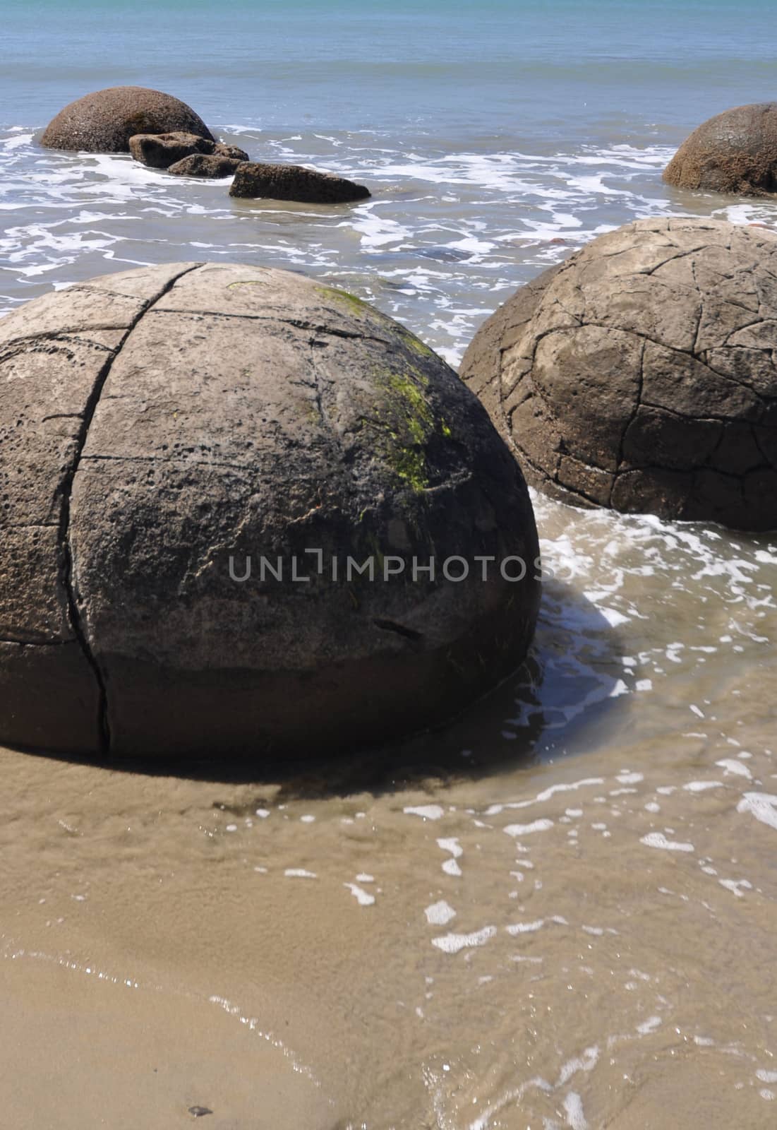 Moeraki Boulders are perfectly spherical rocks on the beach at Moeraki, north of Dunedin, near Oamaru. Up to 13 feet round Maori believe they were food baskets on the original Maori canoe