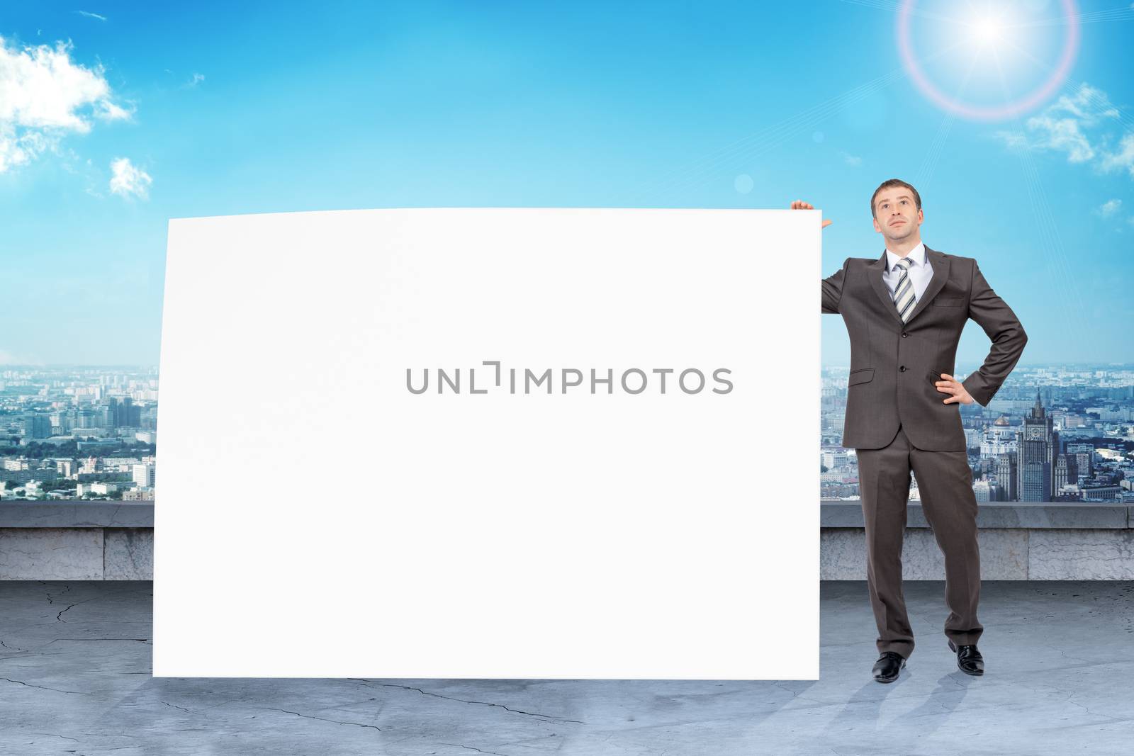 Businessman standing with big paper with blank screen