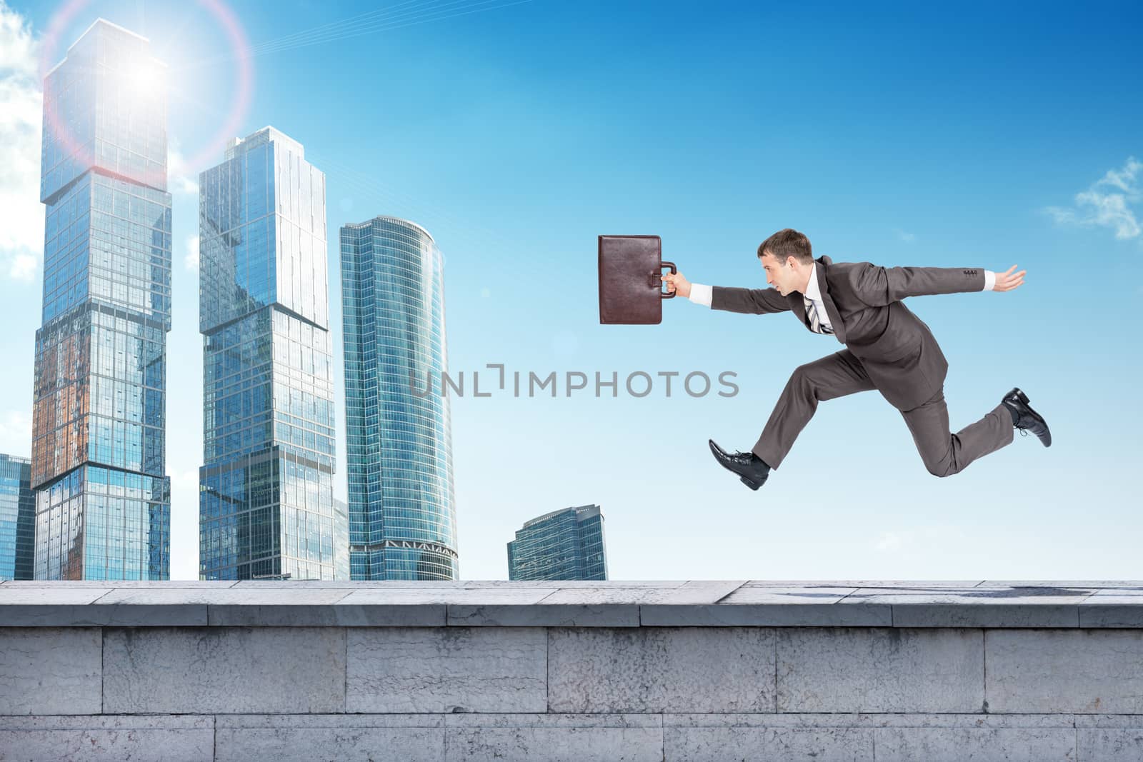 Businessman running forward on building roof. Skyscrapers as background