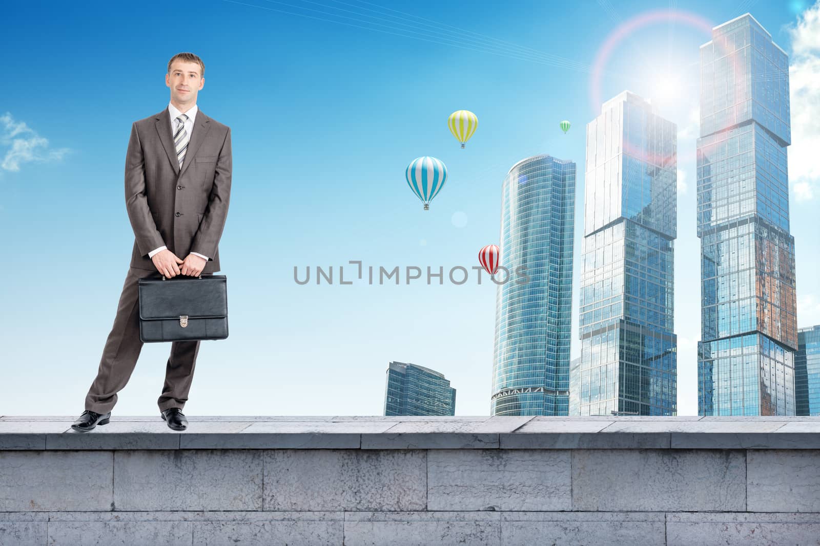 Businessman standing with suitcase on building roof