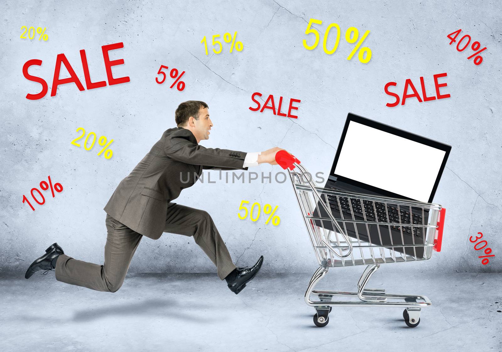 Businessman with laptop in shopping cart on grey background