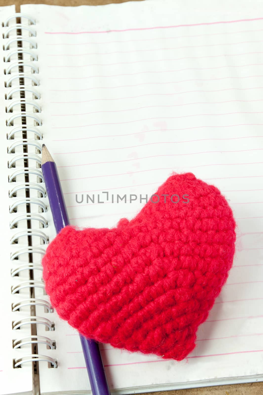 Crochet heart red color and pencil on note book