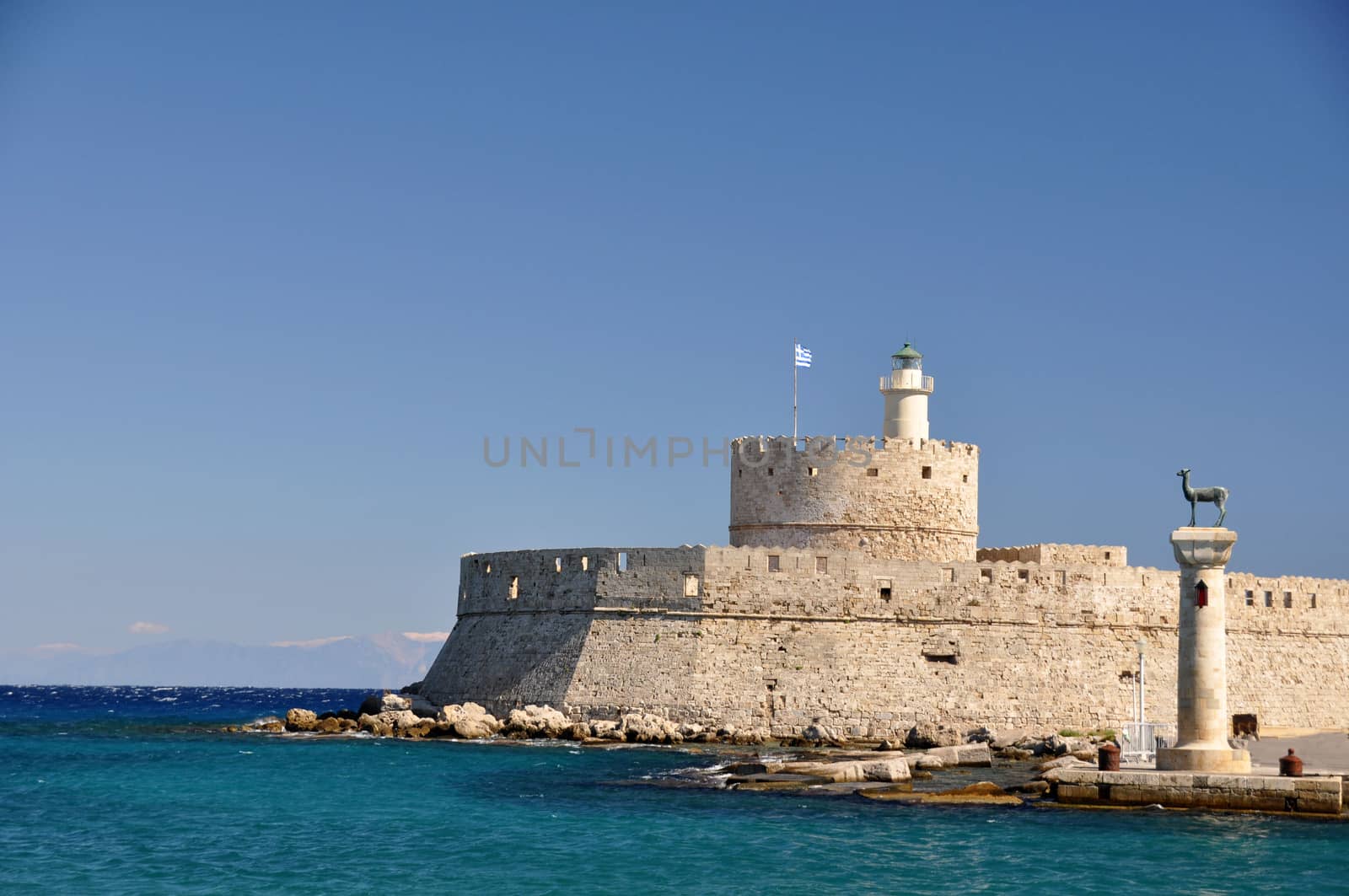 St. Nicholas fortress, now a lighthouse, guards the mouth of Mandraki Harbour on Rhodes. Twin statues of Rhodian deer stand on top of columns either side of the harbour entrance, once the site of the legendary Colossus of Rhodes.