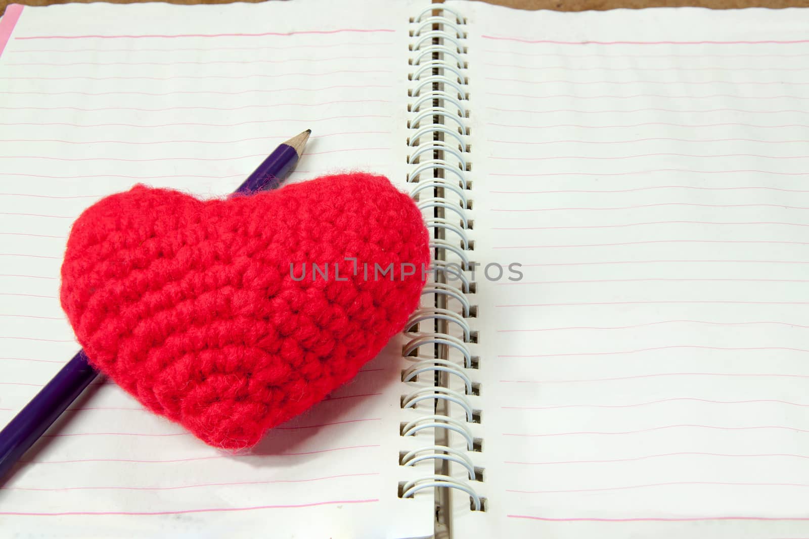 Crochet heart red color and pencil on note book