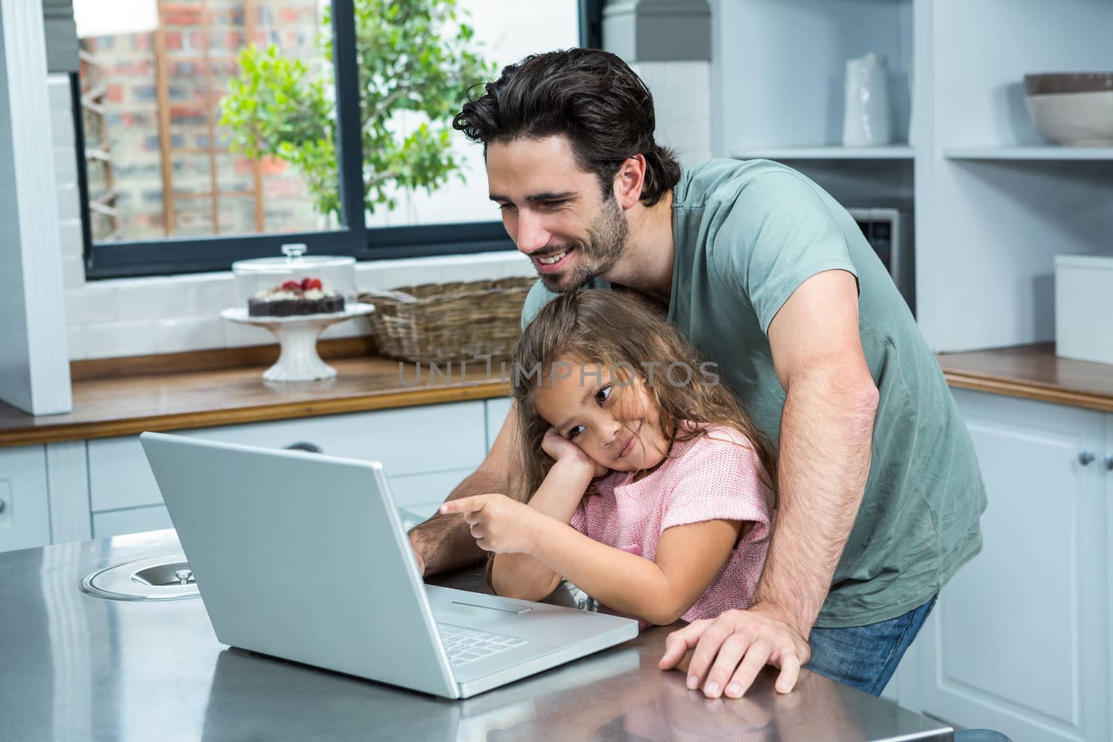 Smiling father and daughter using laptop in the kitchen at home