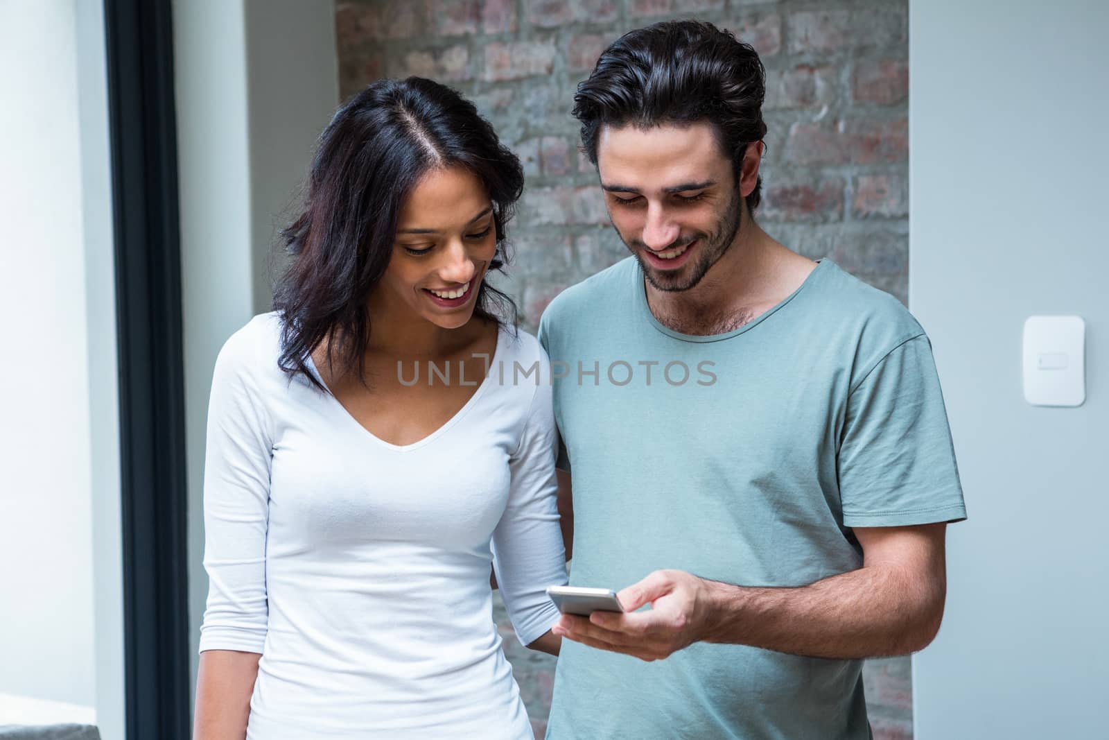 Smiling couple using smartphone together in living room