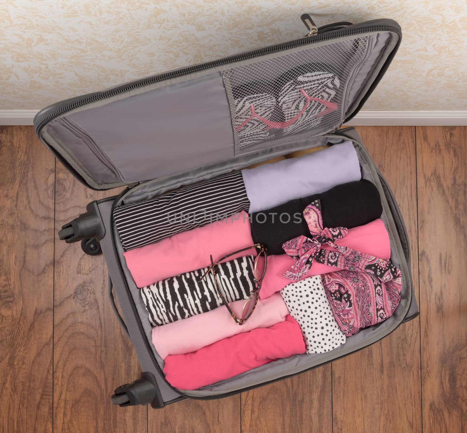 Ladies packed carry-on suitcase with rolled clothes