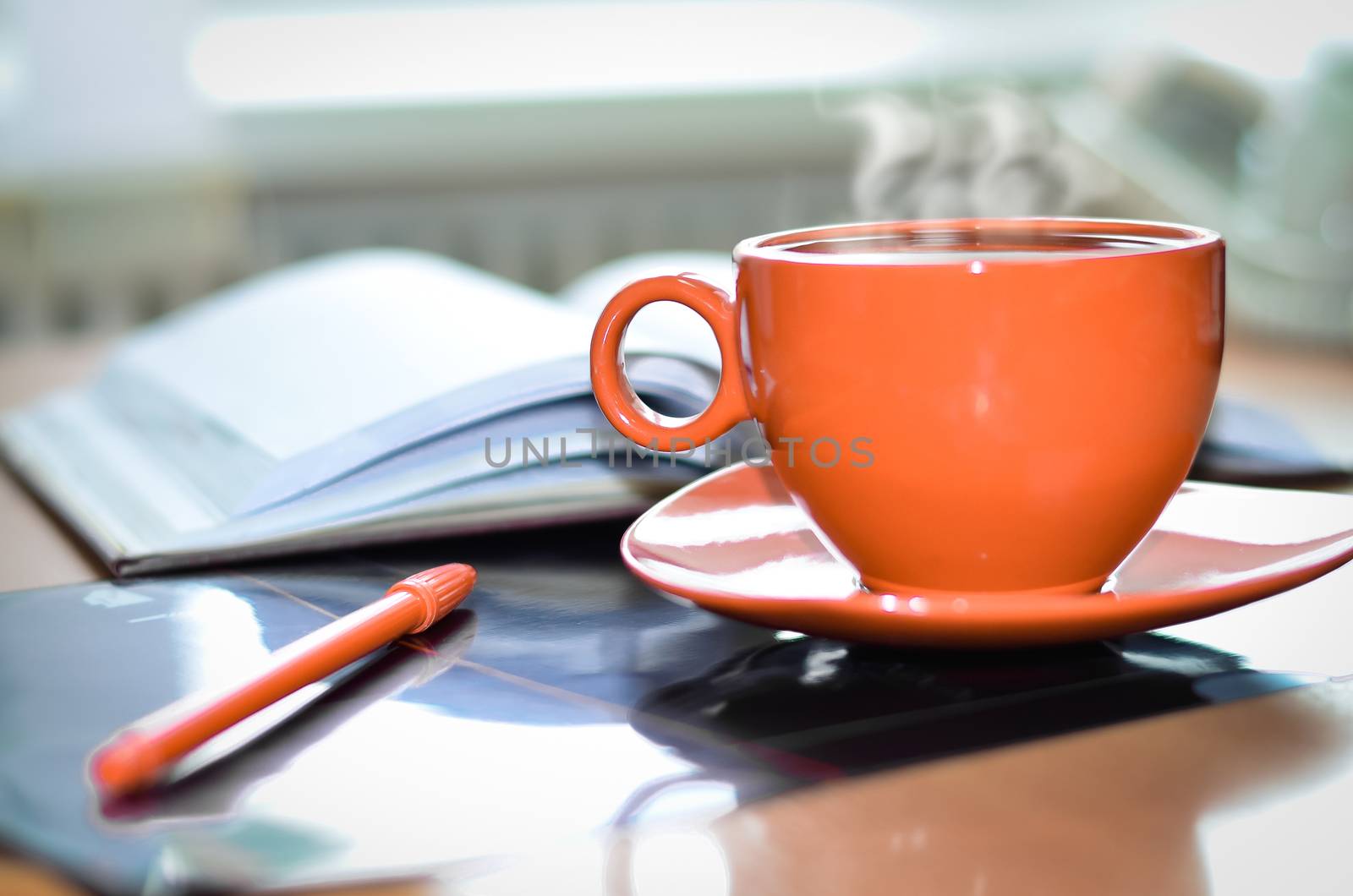 Cup of hot coffee and notepad  on the desktop in the office. 
Focus on the cup. Processing, vintage.