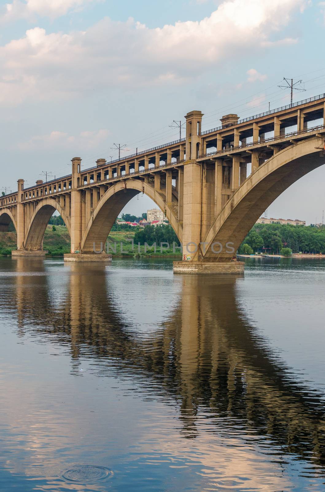 road and rail split-level bridge over the river on a background of blue sky in the city