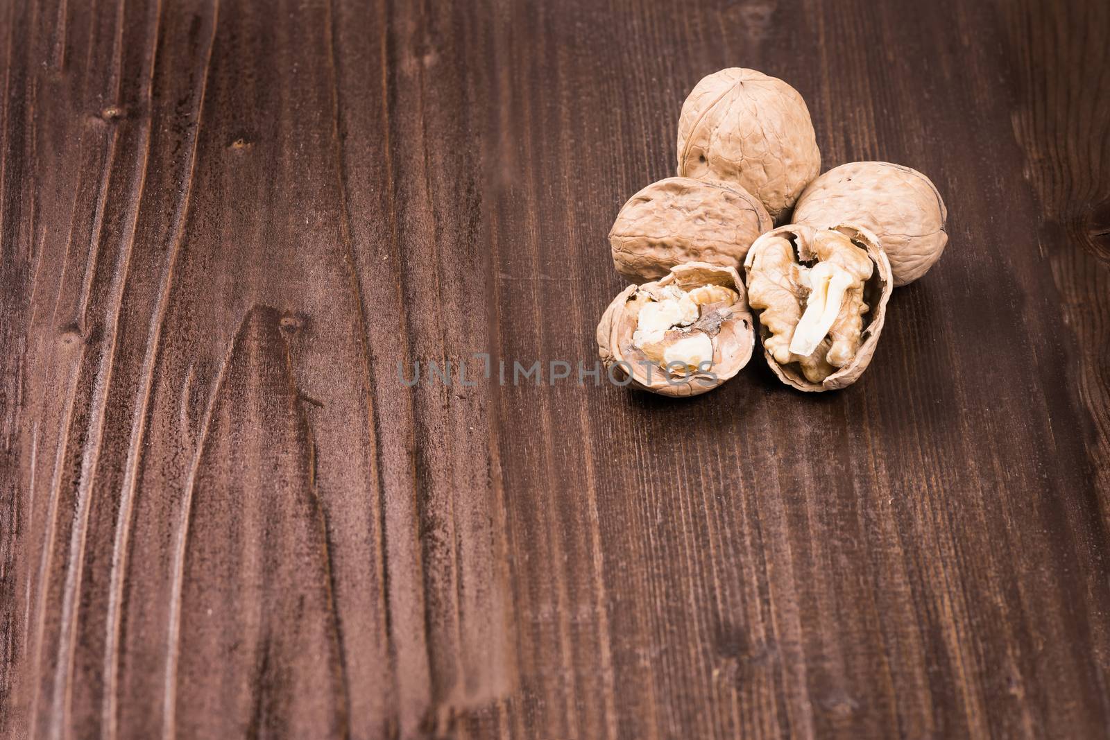 Walnut kernels and whole walnuts on rustic old wooden table