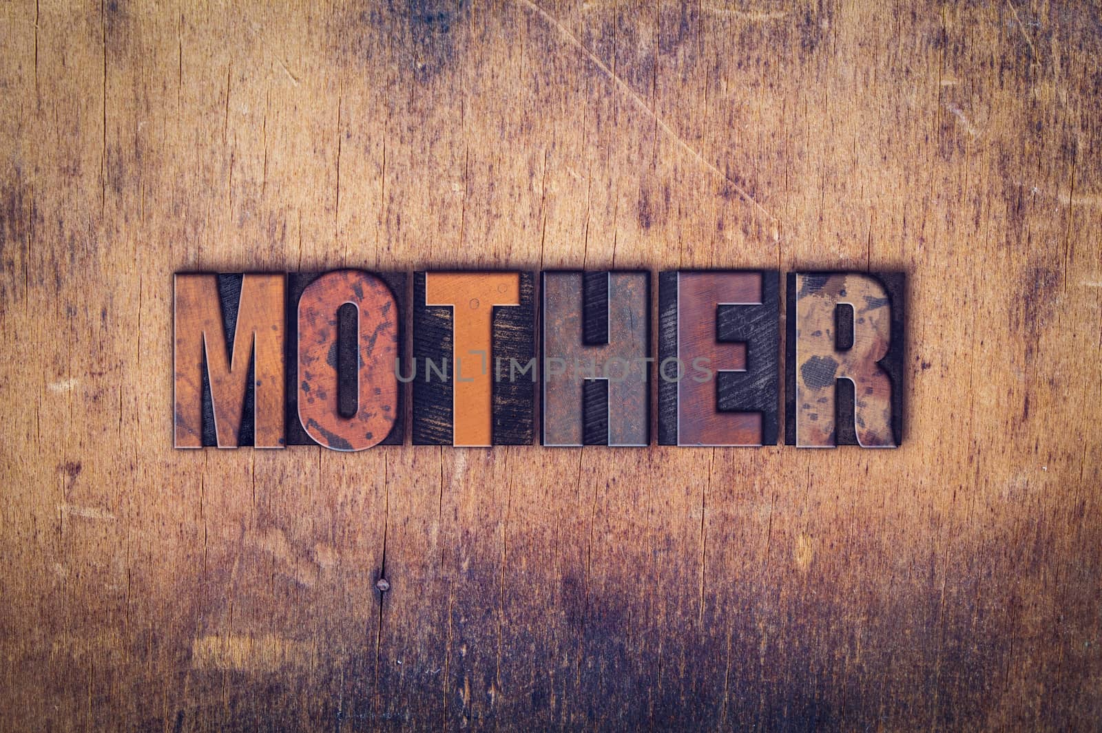 The word "Mother" written in dirty vintage letterpress type on a aged wooden background.
