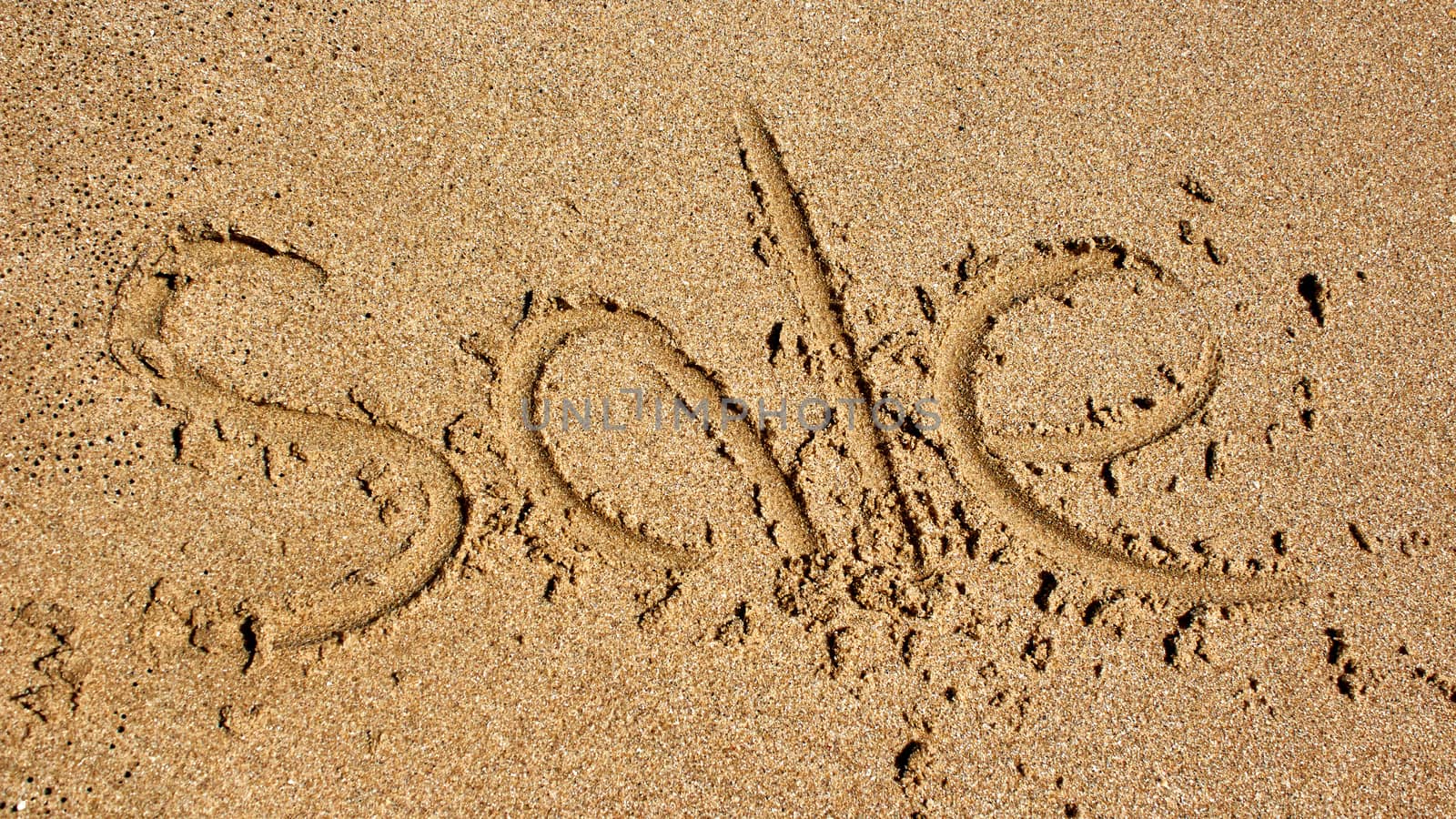 Word sale handwritten in sand at beach.