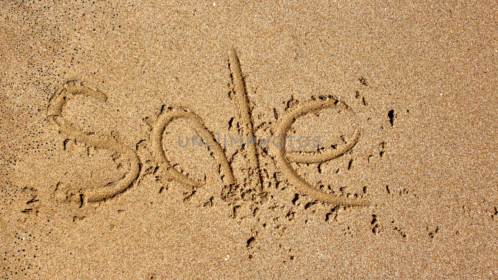 Word sale handwritten in sand at beach.