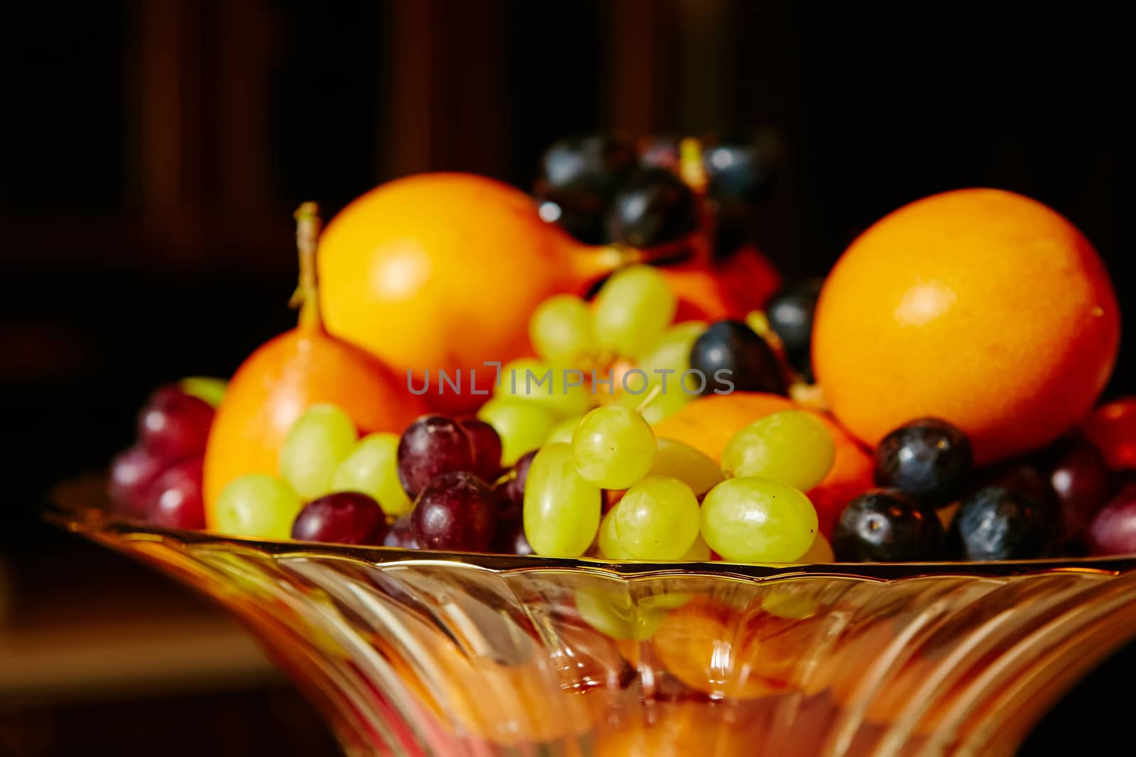 Assortment of juicy fruits on wooden table, on black background