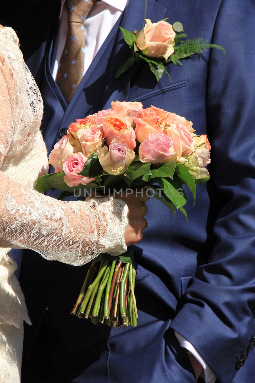 A bride holding her bouquet, roses in various shades of pink