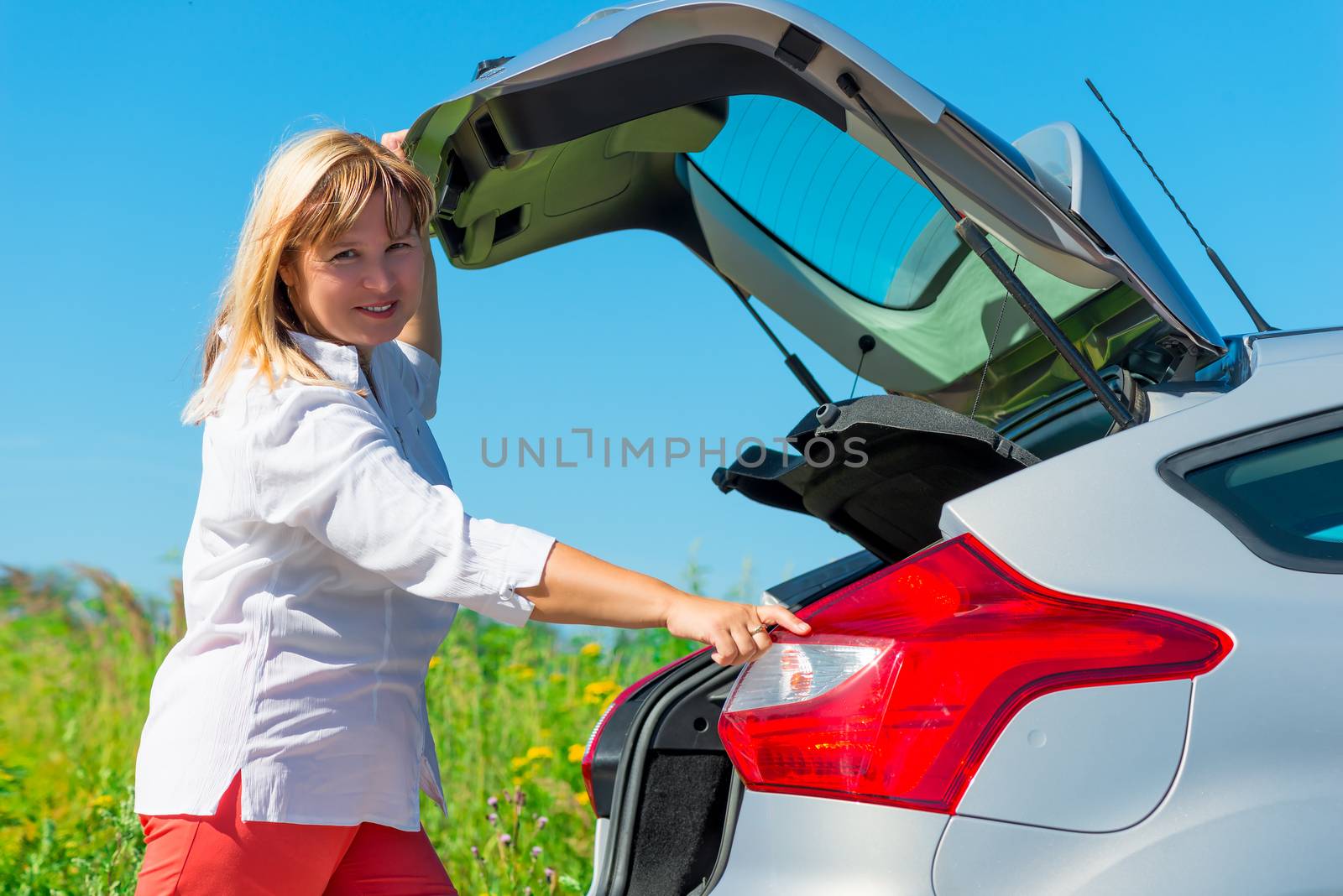 Woman closes the trunk of the car type hatchback
