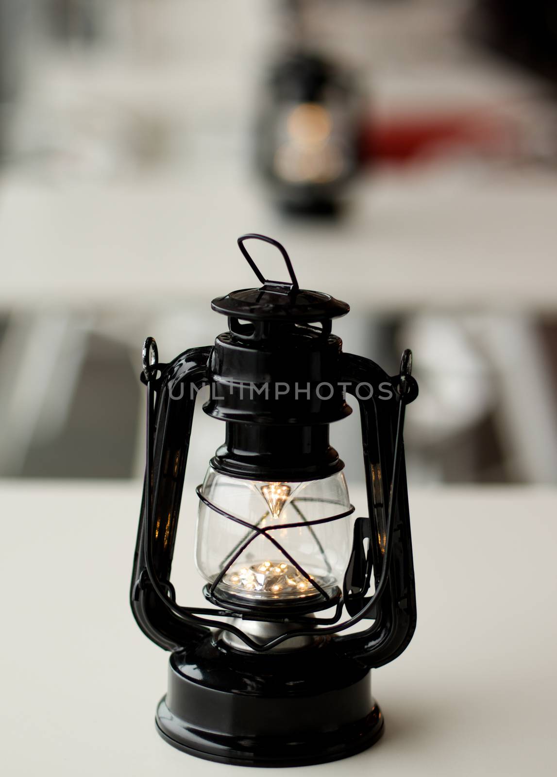 Old Fashioned Street Cafe Lantern on White Table closeup. Focus on Foreground