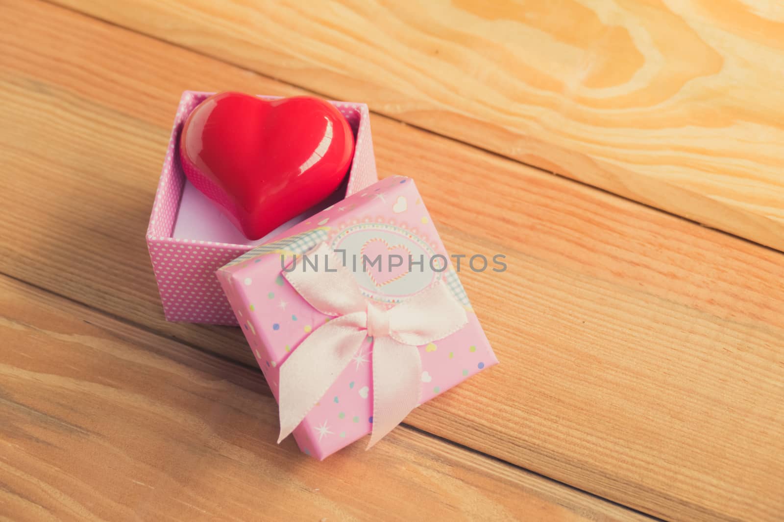 Gift of love. hearty gift. A gift box with a red heart inside. On the wooden floor