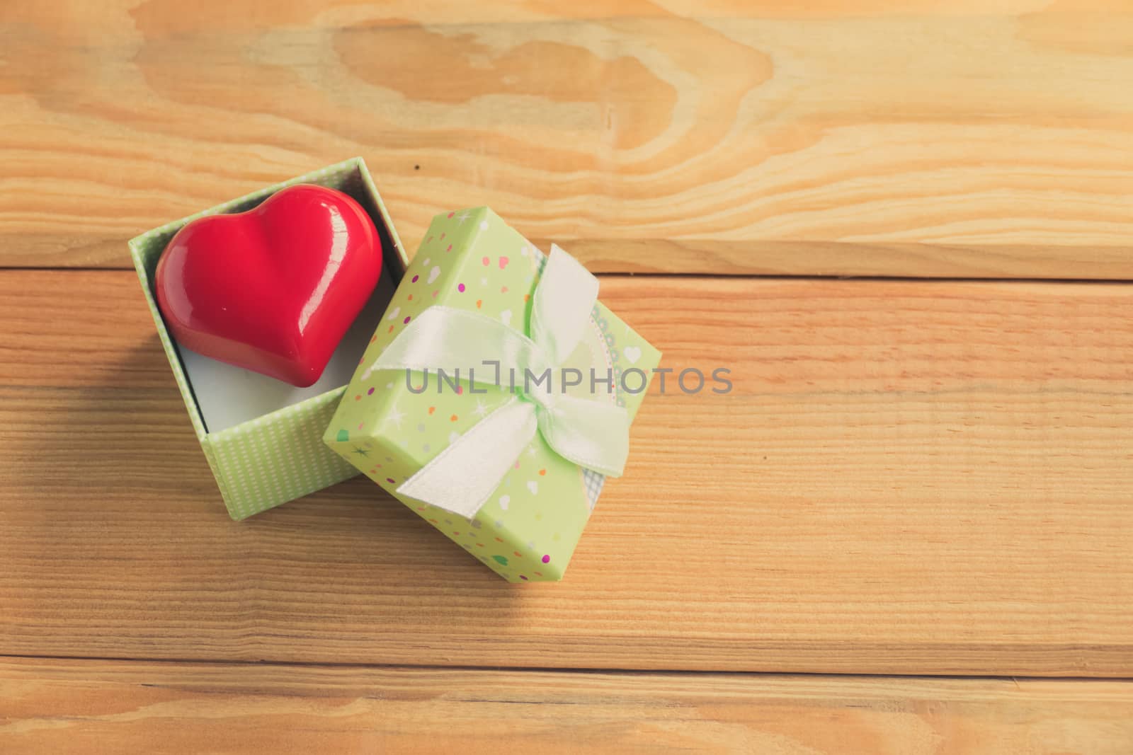 Gift of love. hearty gift. A gift box with a red heart inside. On the wooden floor