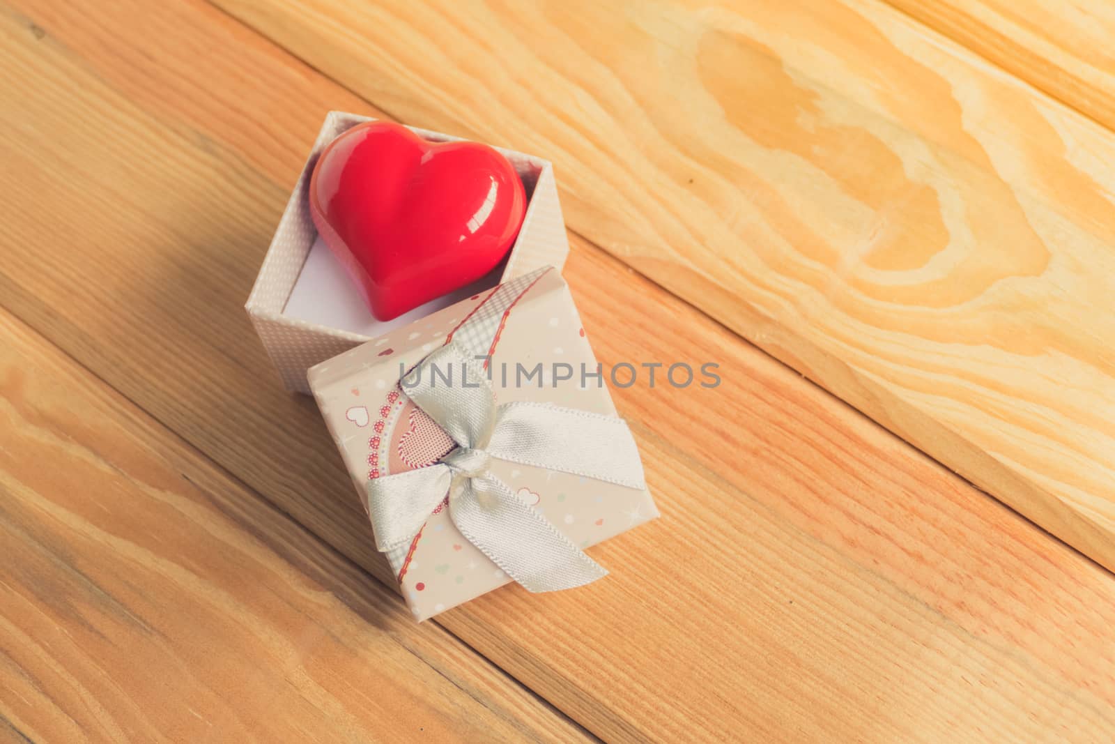 Gift of love. hearty gift. A gift box with a red heart inside. On the wooden floor