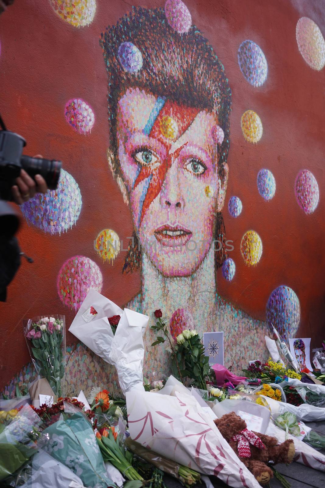 UNITED KINGDOM, London: Fans leave flowers and candles to pay tribute to British singer David Bowie, following the announcement of Bowie's death, in Brixton, south London, on January 11, 2016. British music icon David Bowie died of cancer at the age of 69, drawing an outpouring of tributes for the innovative star famed for groundbreaking hits like Ziggy Stardust and his theatrical shape-shifting style. 