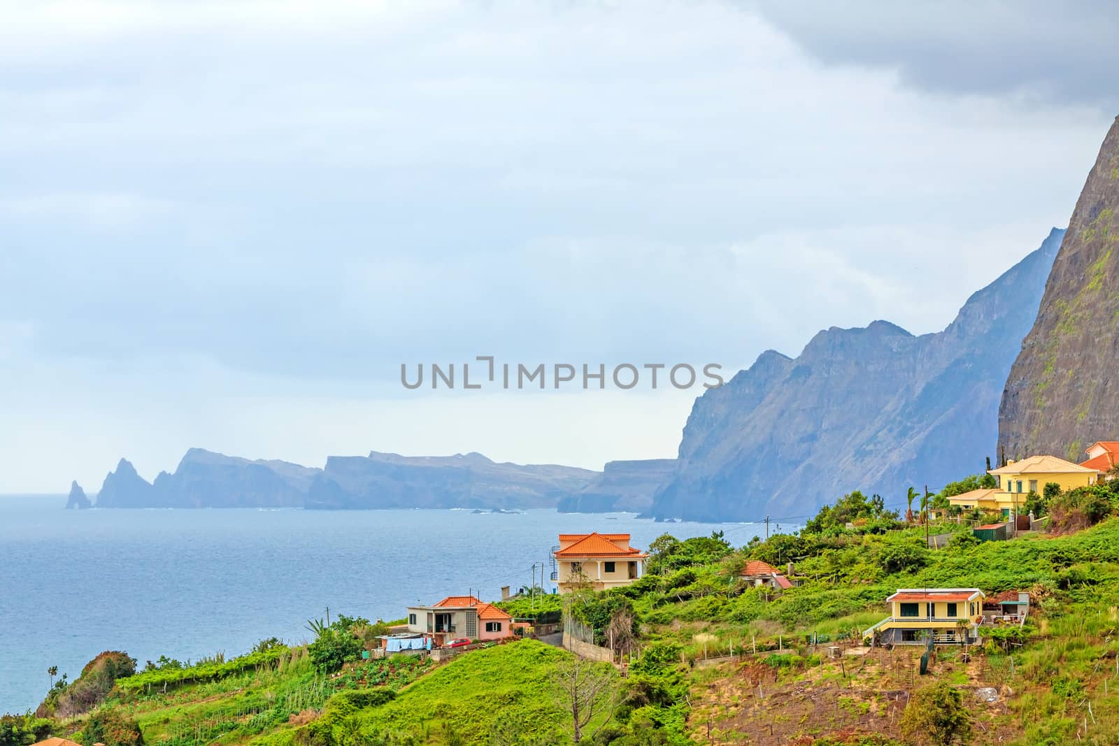 Faial, Madeira - June 7, 2013: View over the coast near village Faial, in the north of Madeira. Typical rural houses in the foreground