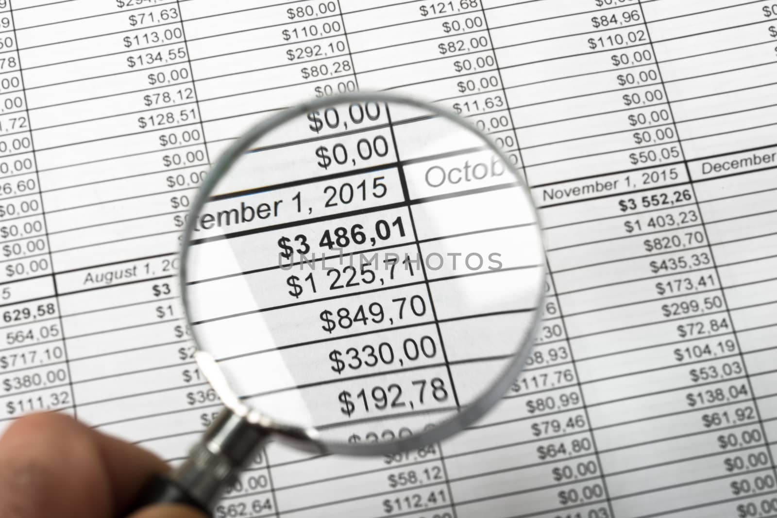 Man holding magnifier on bills background, close up view