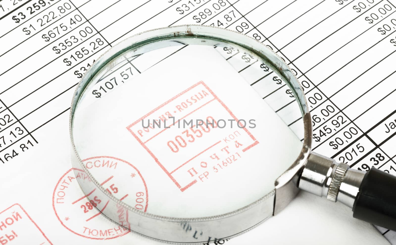 Magnifier with envelope on bills background, close up view