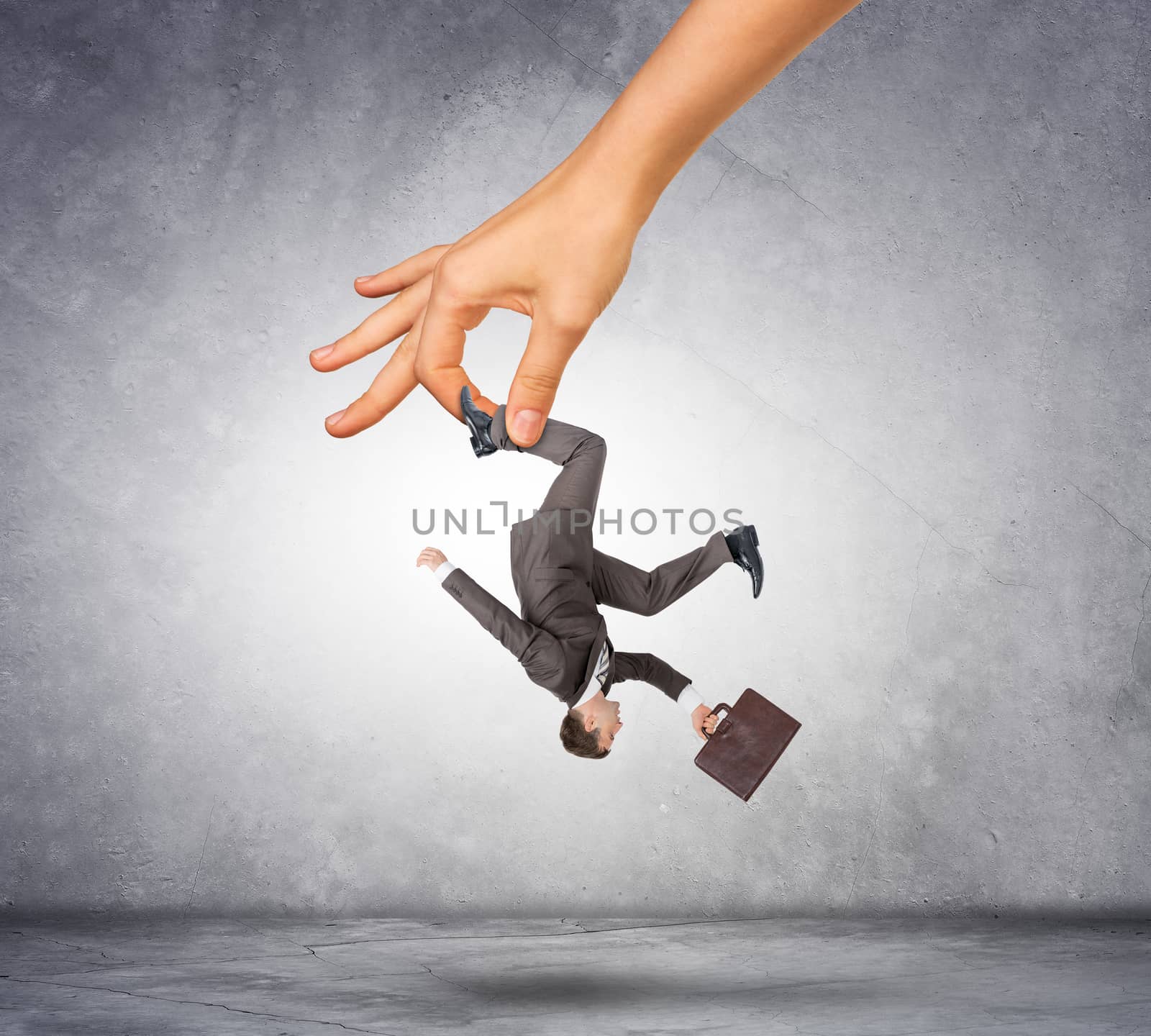 Female hand holding businessman on grey background