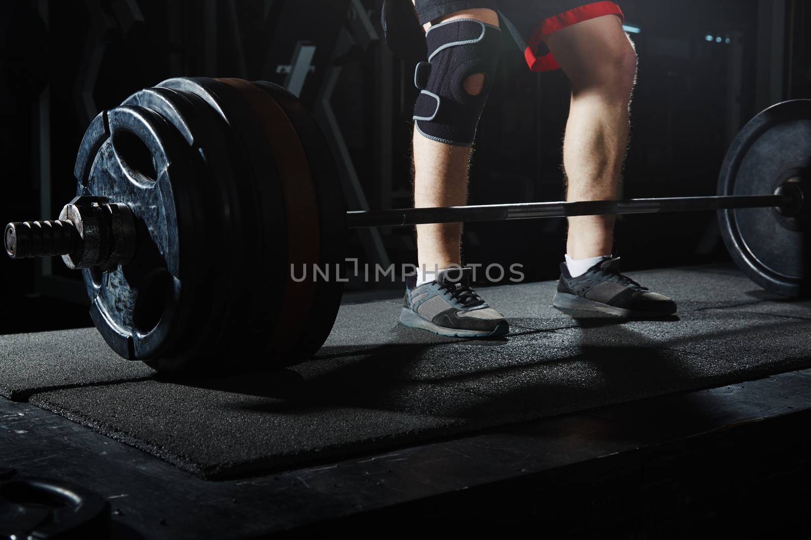 Man at the heavy barbell in fitness club. Close-up view