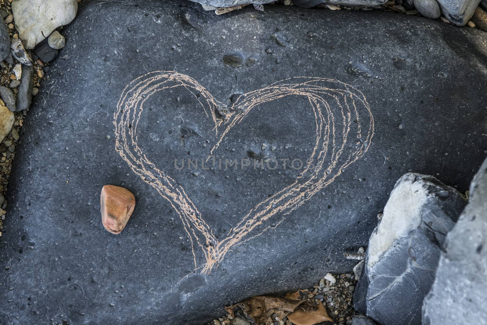 Love heart drawn onto a large black rock at the beach.