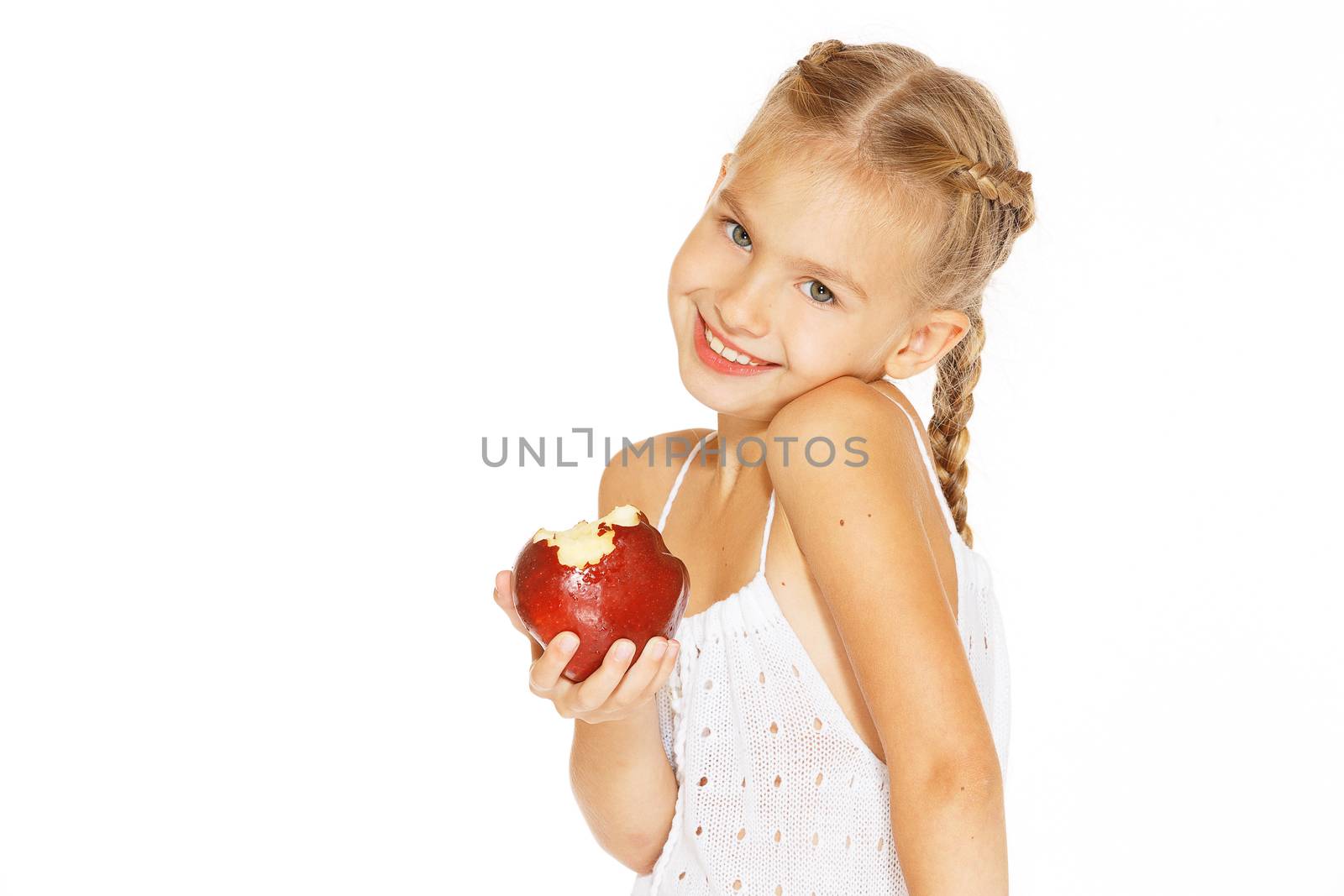 Cute little girl in a white dress bites red fresh apple