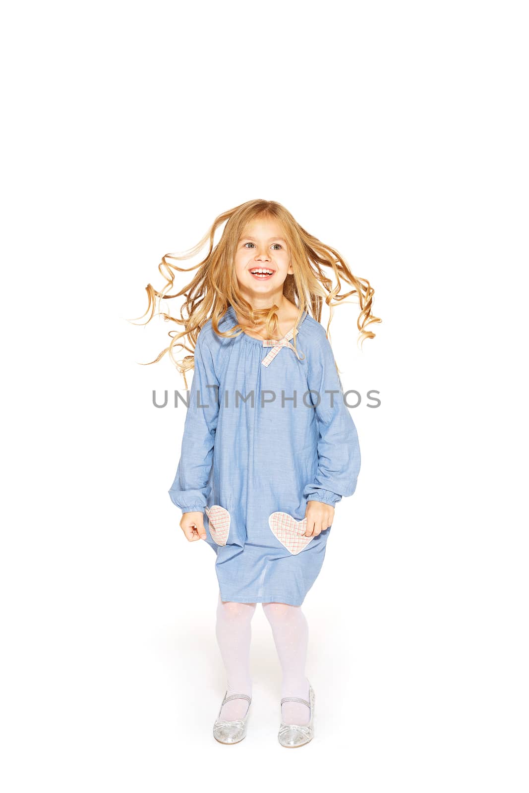 Jumping little girl in a blue dress with flying curls