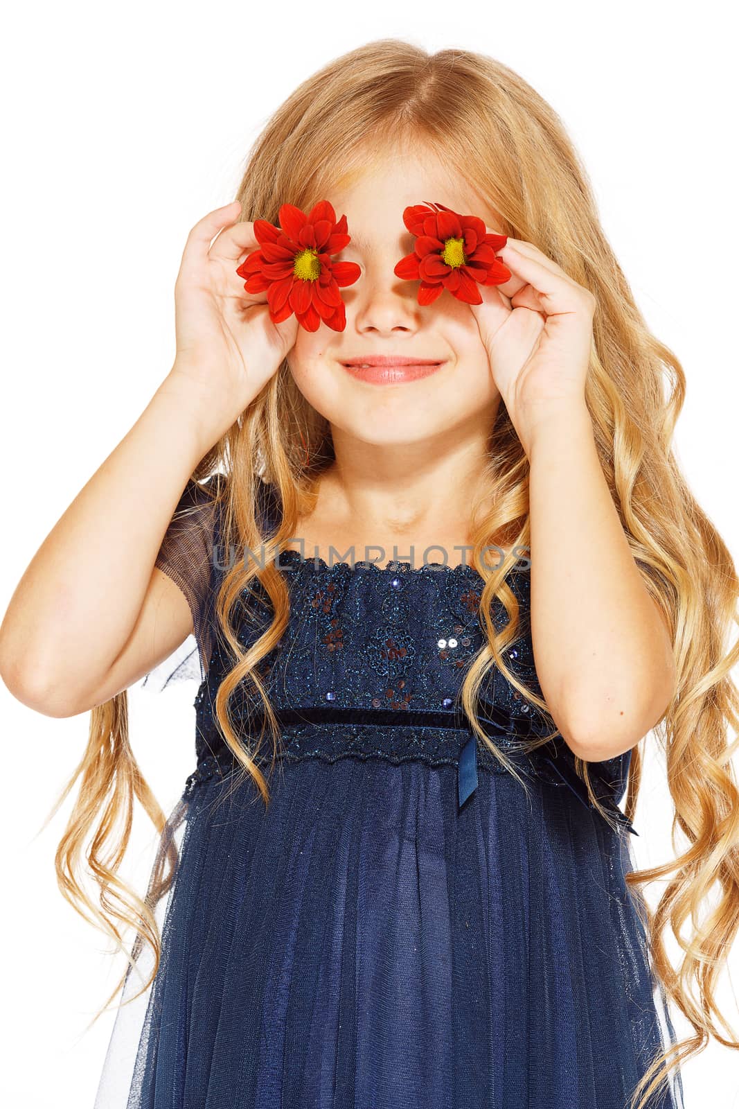 Little cute girl holding two red flowers near her eyes