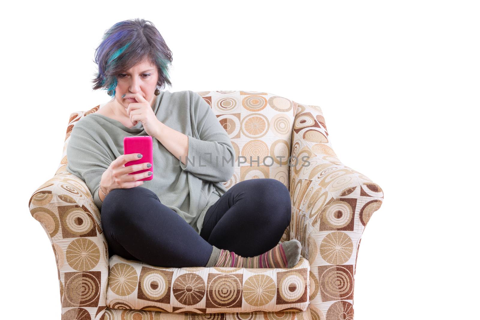 Single middle-aged plump woman with concerned expression looking at phone on comfy sofa