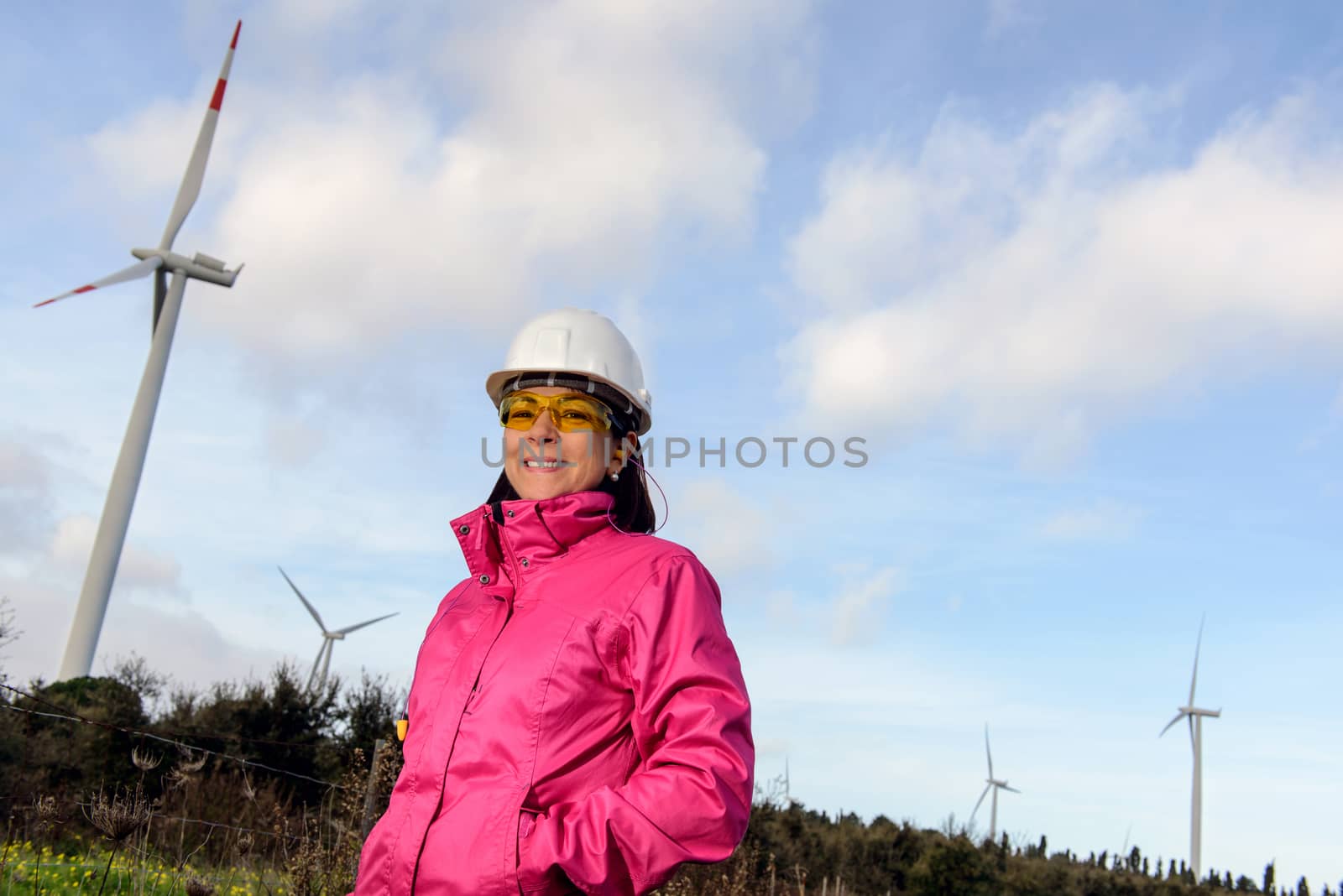 Engineer woman checking production, with laptops, wind turbines on the site.