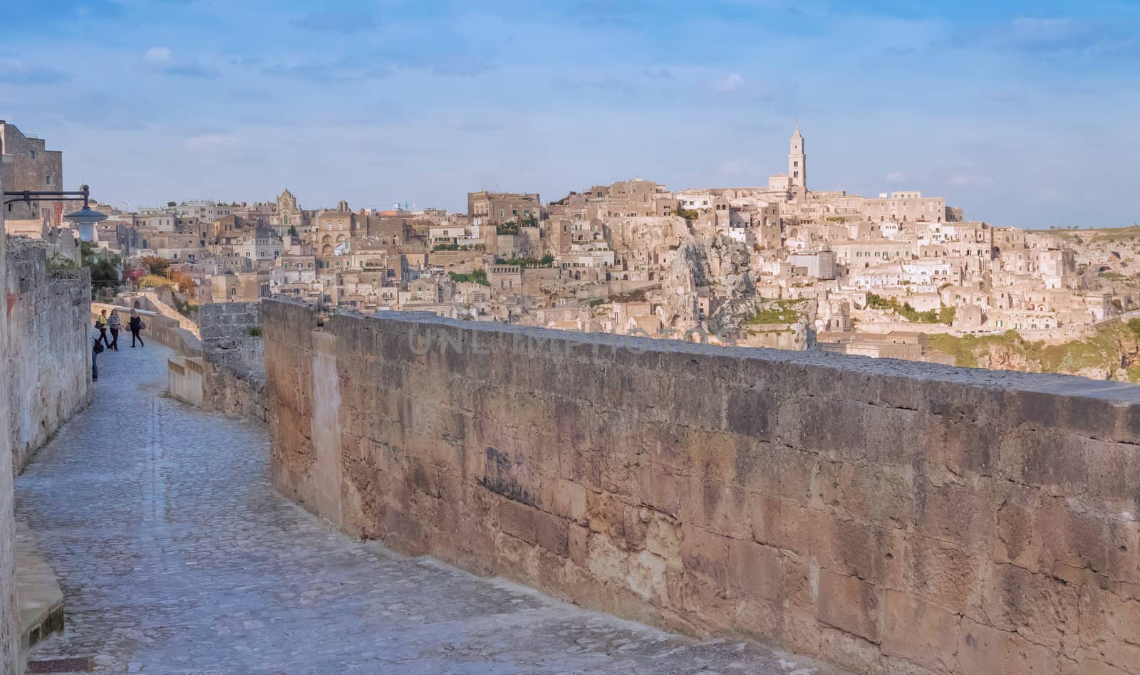panoramic view of typical stones and church of Matera shot from typical old street, under blu sky. Basilicata, Italy