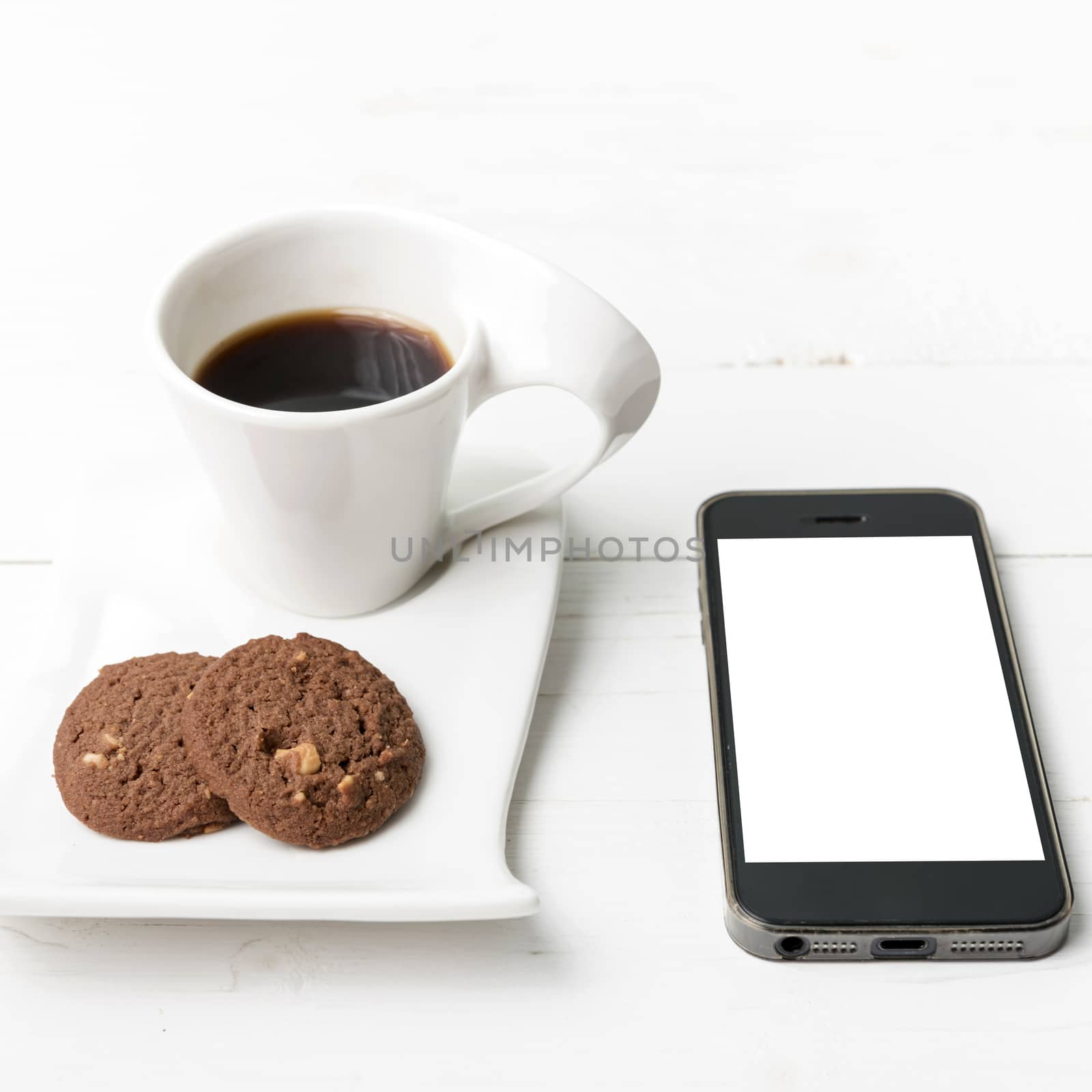 coffee cup with cookie and phone on white wood background