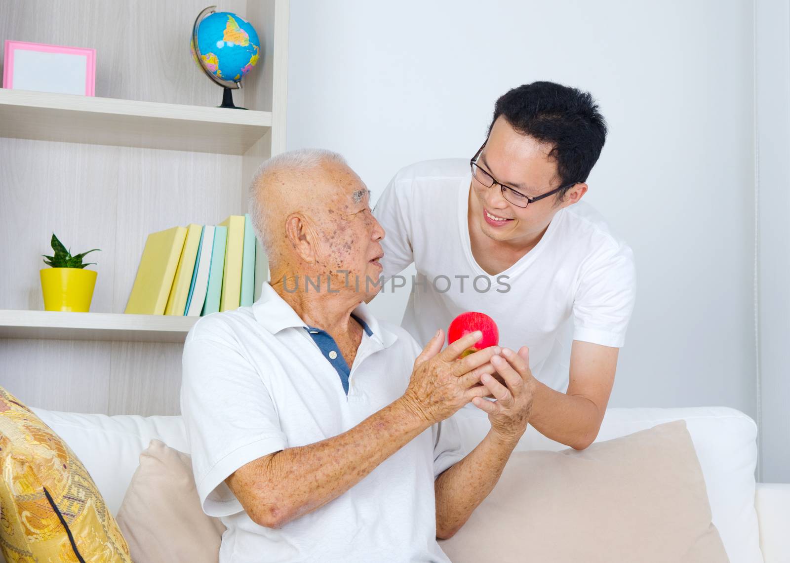 Asian senior man talking with his son while holding an apple