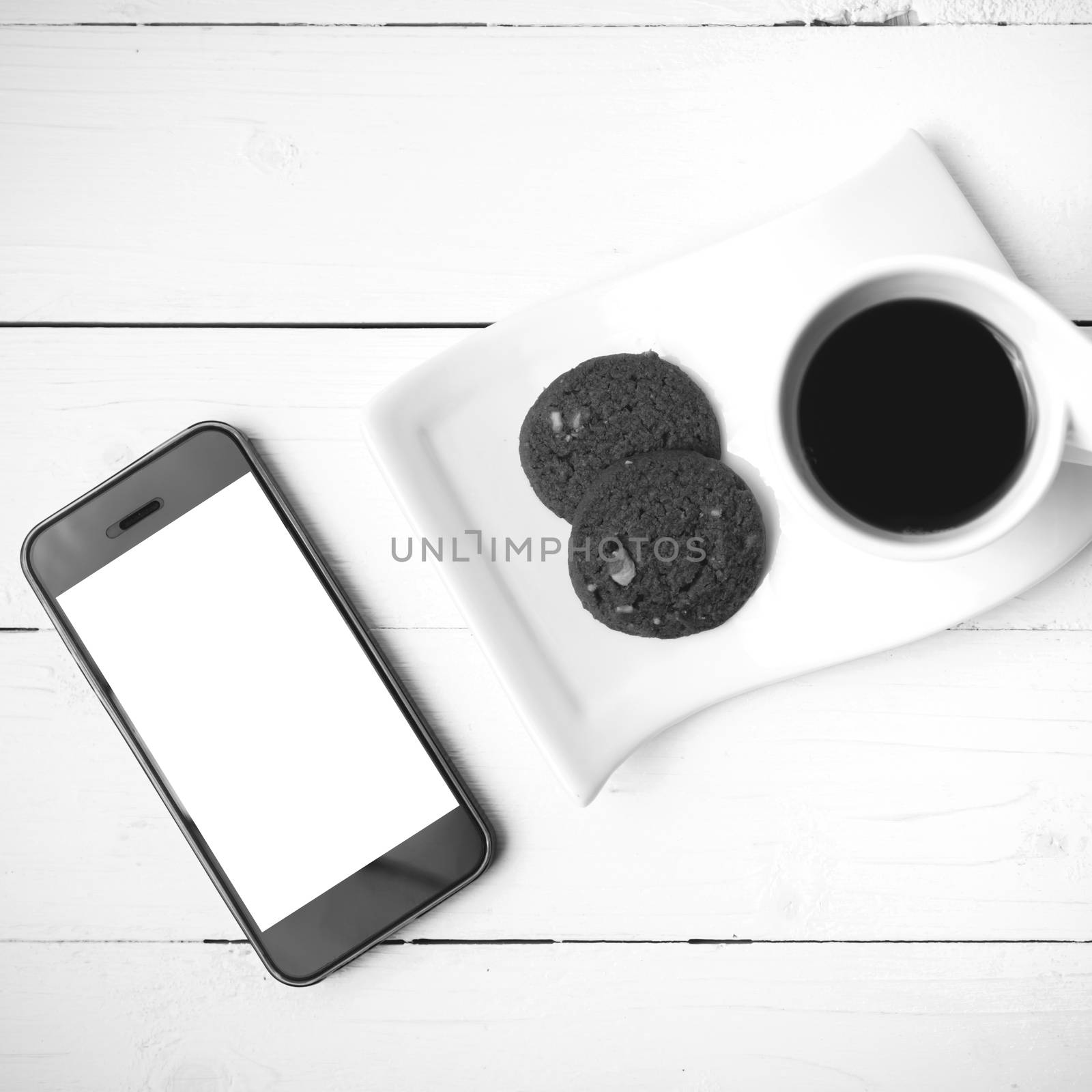 coffee cup with cookie and phone on white wood black and white color