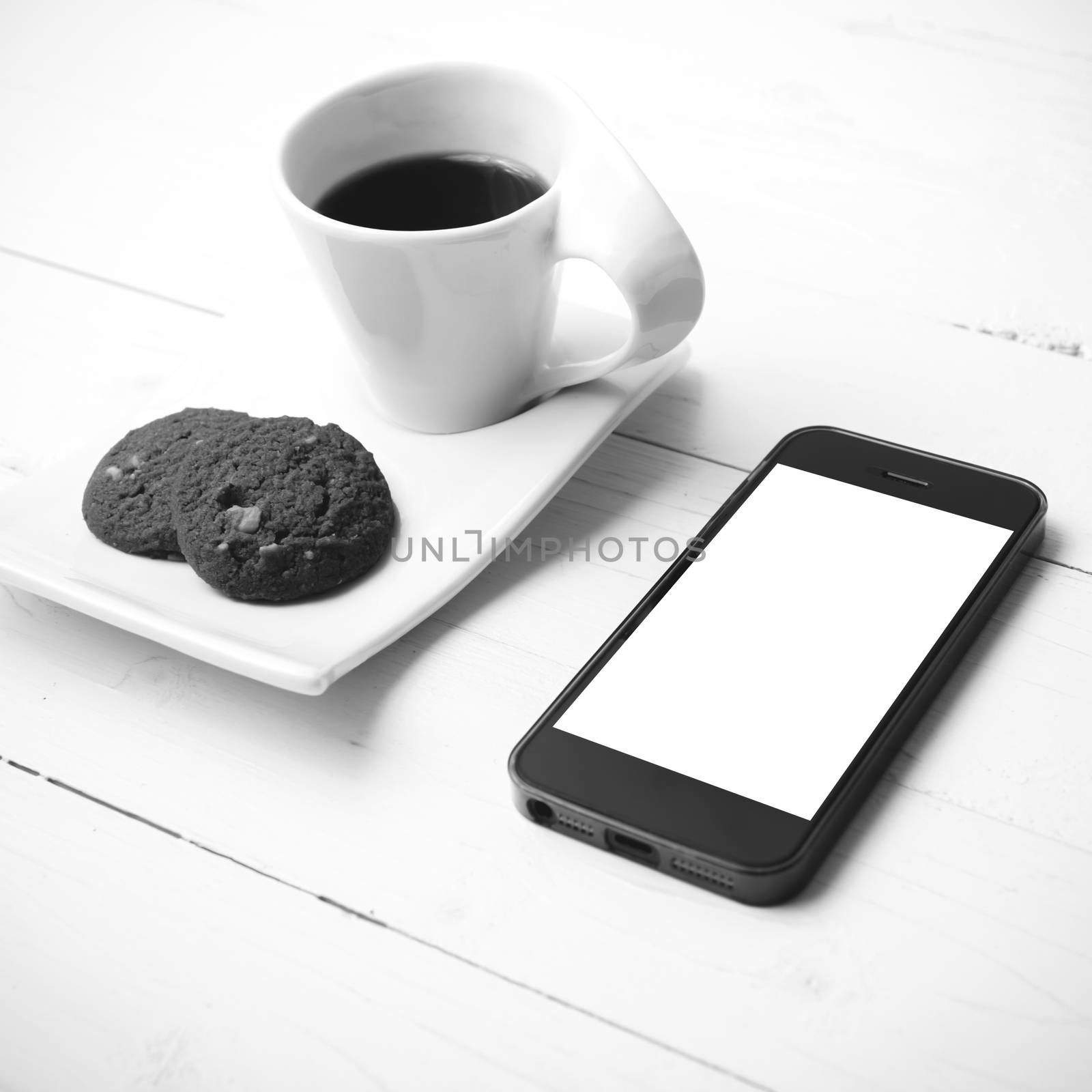 coffee cup with cookie and phone on white wood black and white color