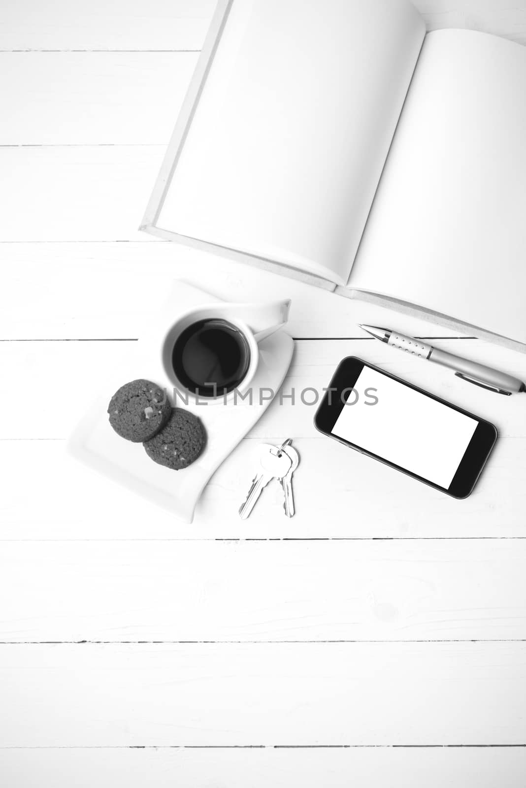 coffee cup with cookie,phone,notebook and key on white wood table black and white color