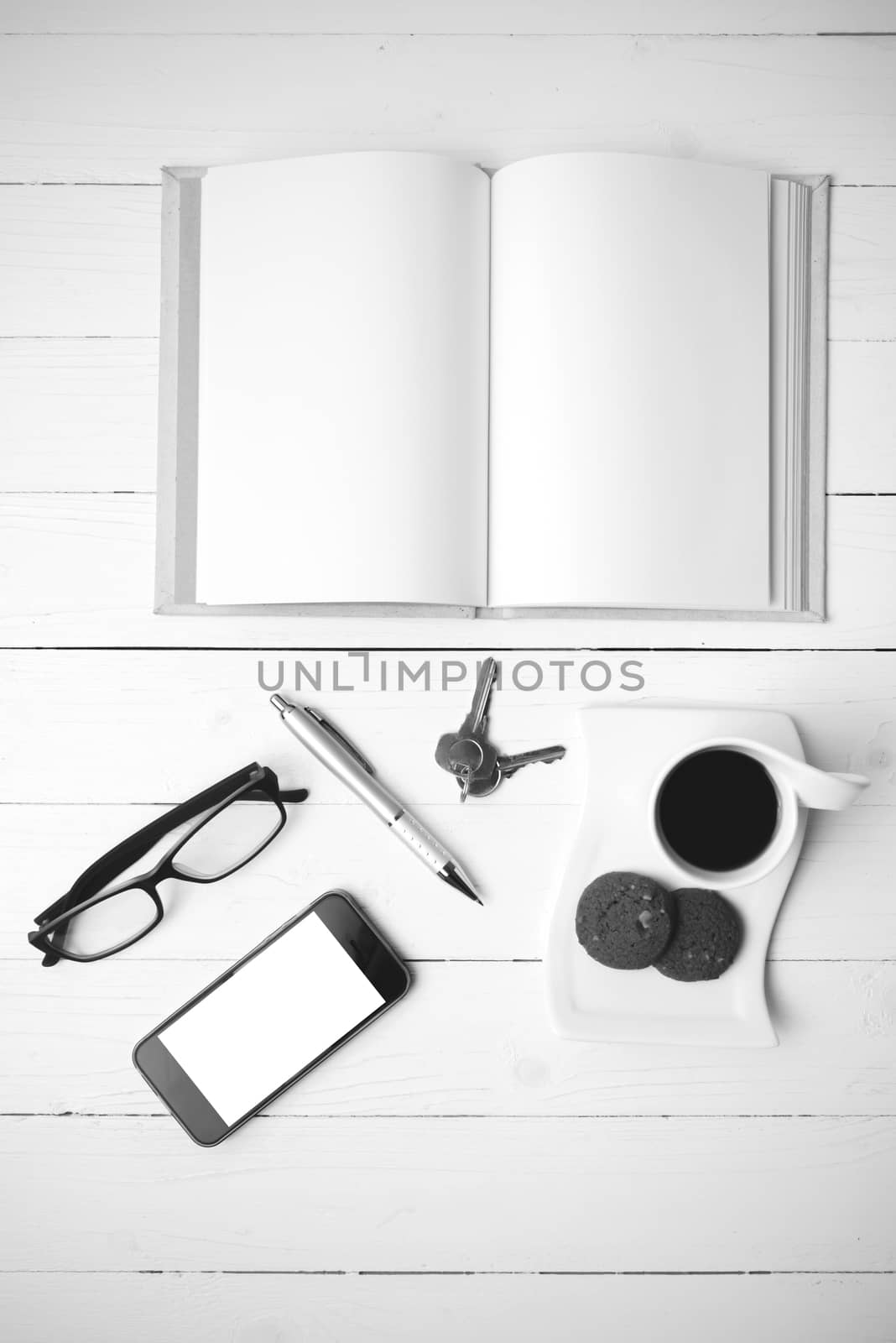 coffee cup with cookie,phone,open notebook and eyeglasses on white wood table black and white color