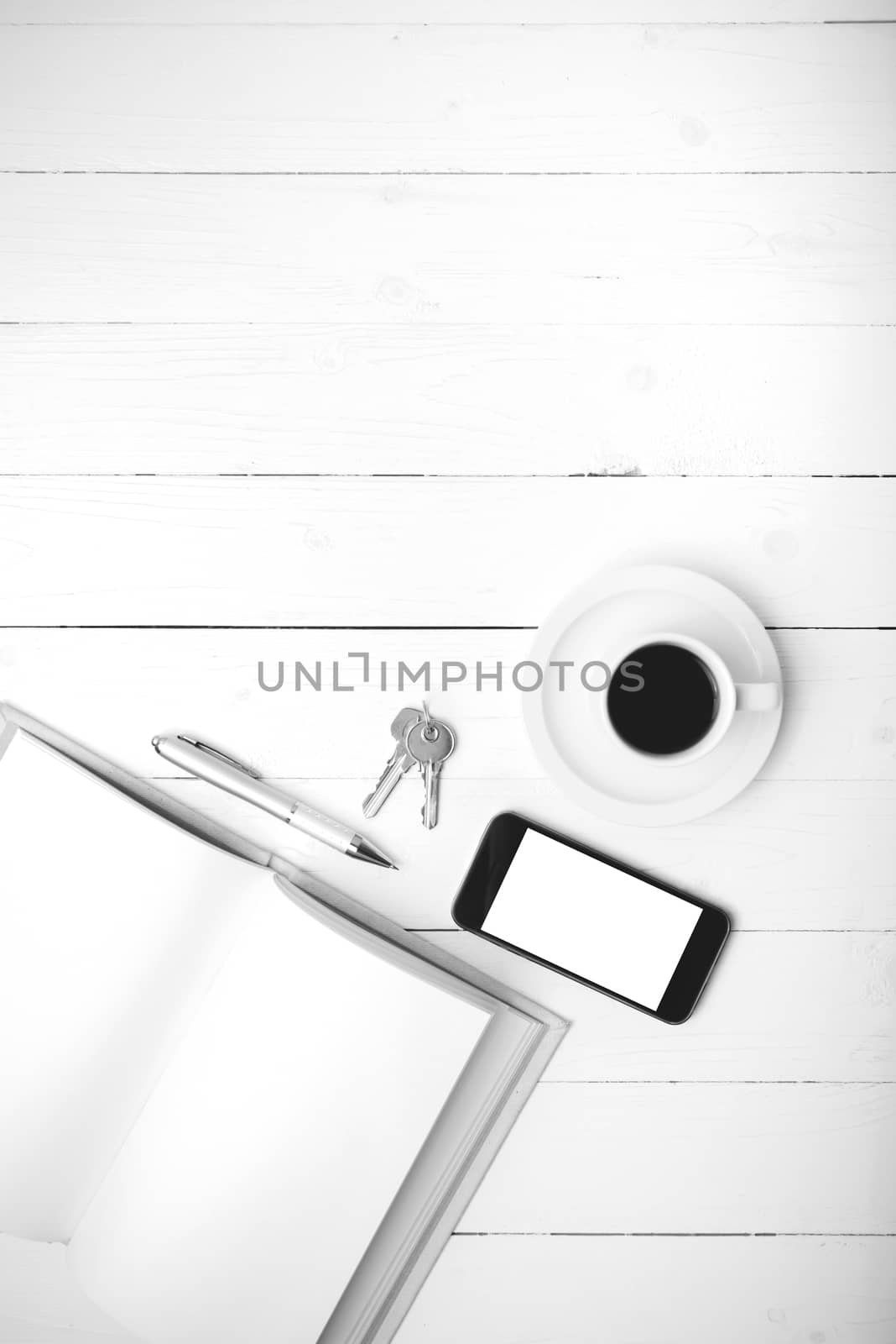 coffee cup with phone, key and open notebook on white wood table black and white color