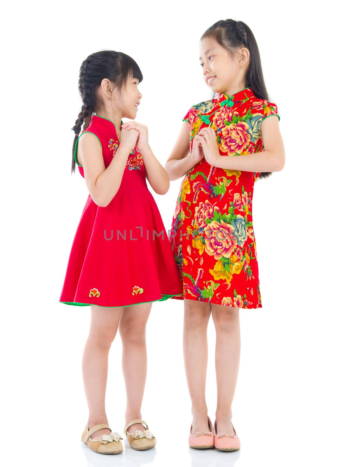 Happy Chinese New Year! Chinese girls in traditional Chinese cheongsam greeting to each other, isolated on white background